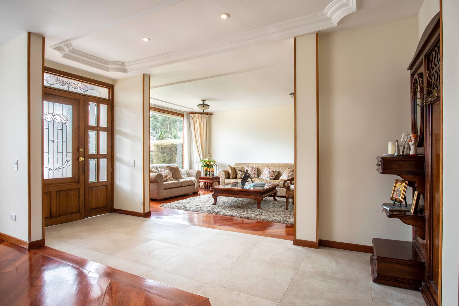 Home entry hall with a wood-framed glass door opening to a living room, with hardwood and tile floors