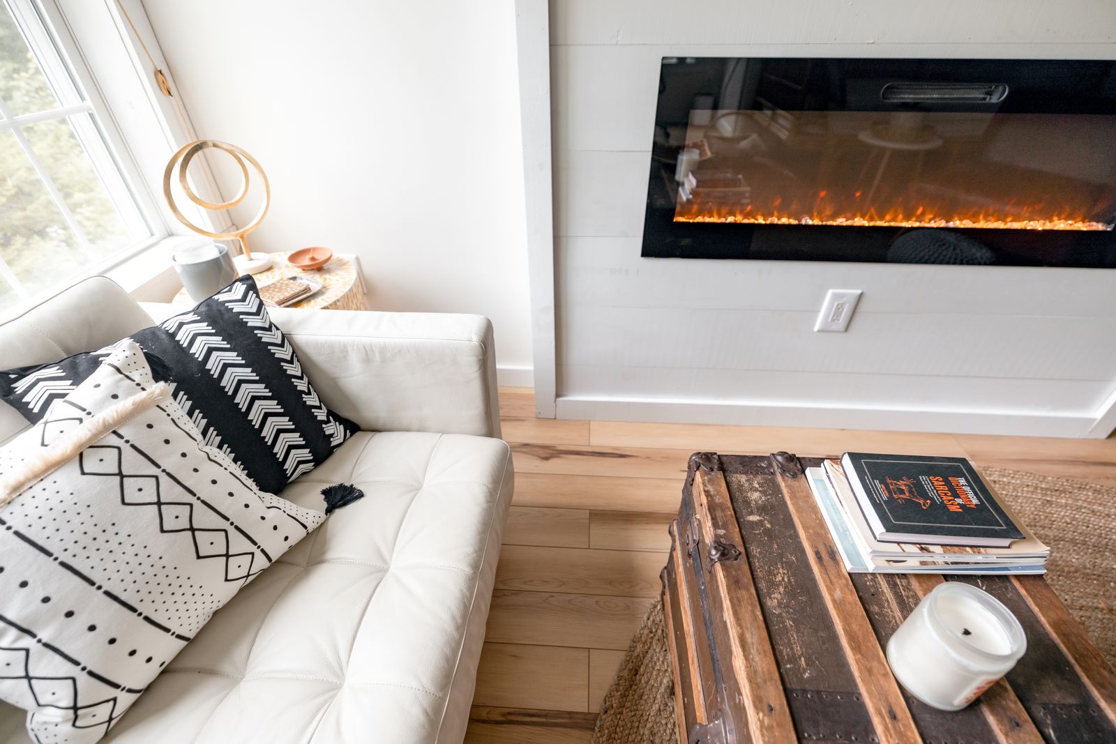 Bright living room with a white sofa beside a fireplace in a well-kept New Hampshire rental home