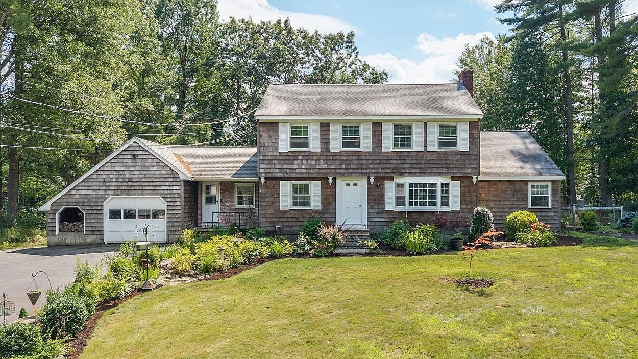 Front exterior of 17 Reeds Ferry Way, a cedar-shingled Colonial in Merrimack NH with an attached two-car garage and landscaped yard