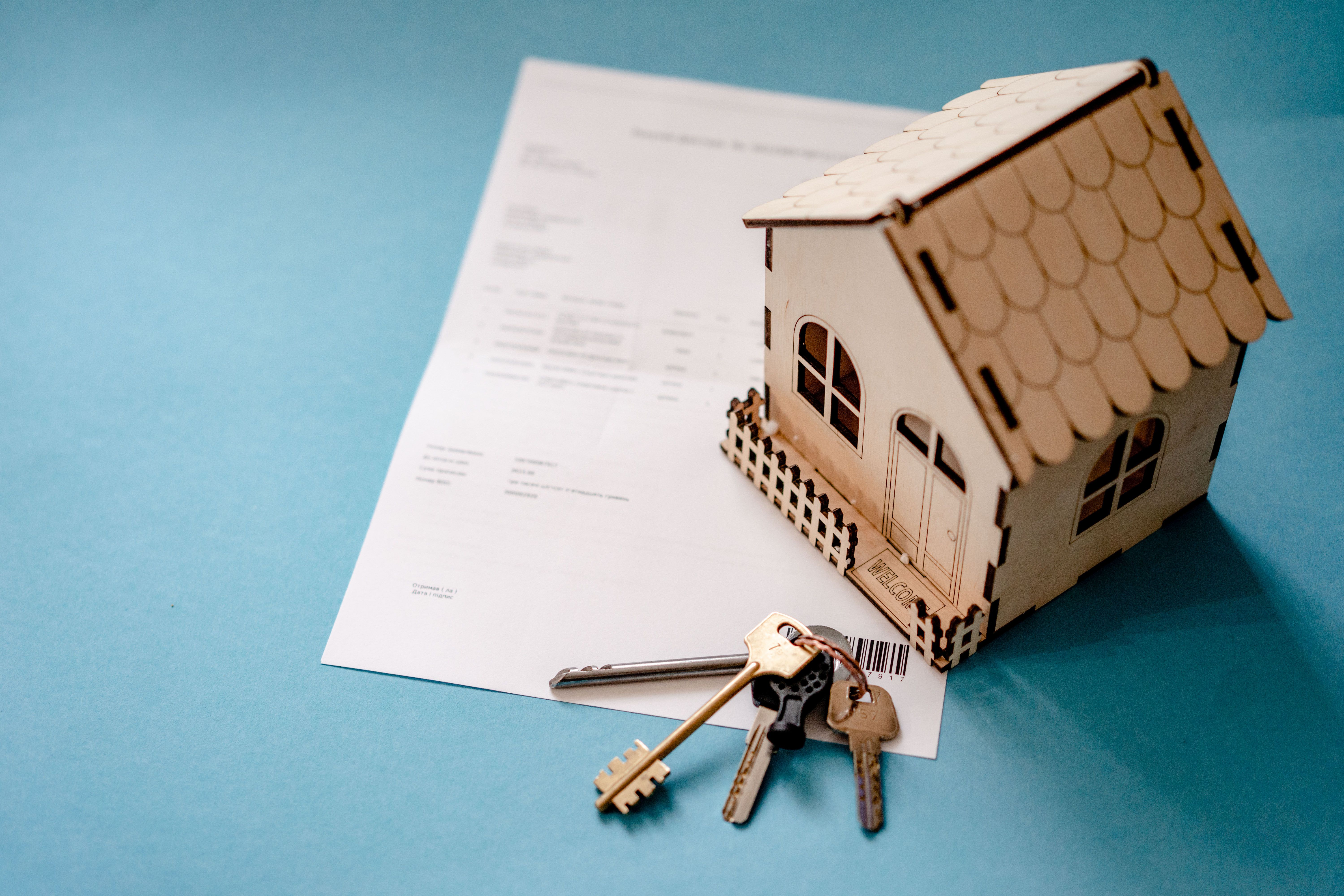 Wooden model house with keys resting on a signed contract, illustrating how long closing takes on a New Hampshire home