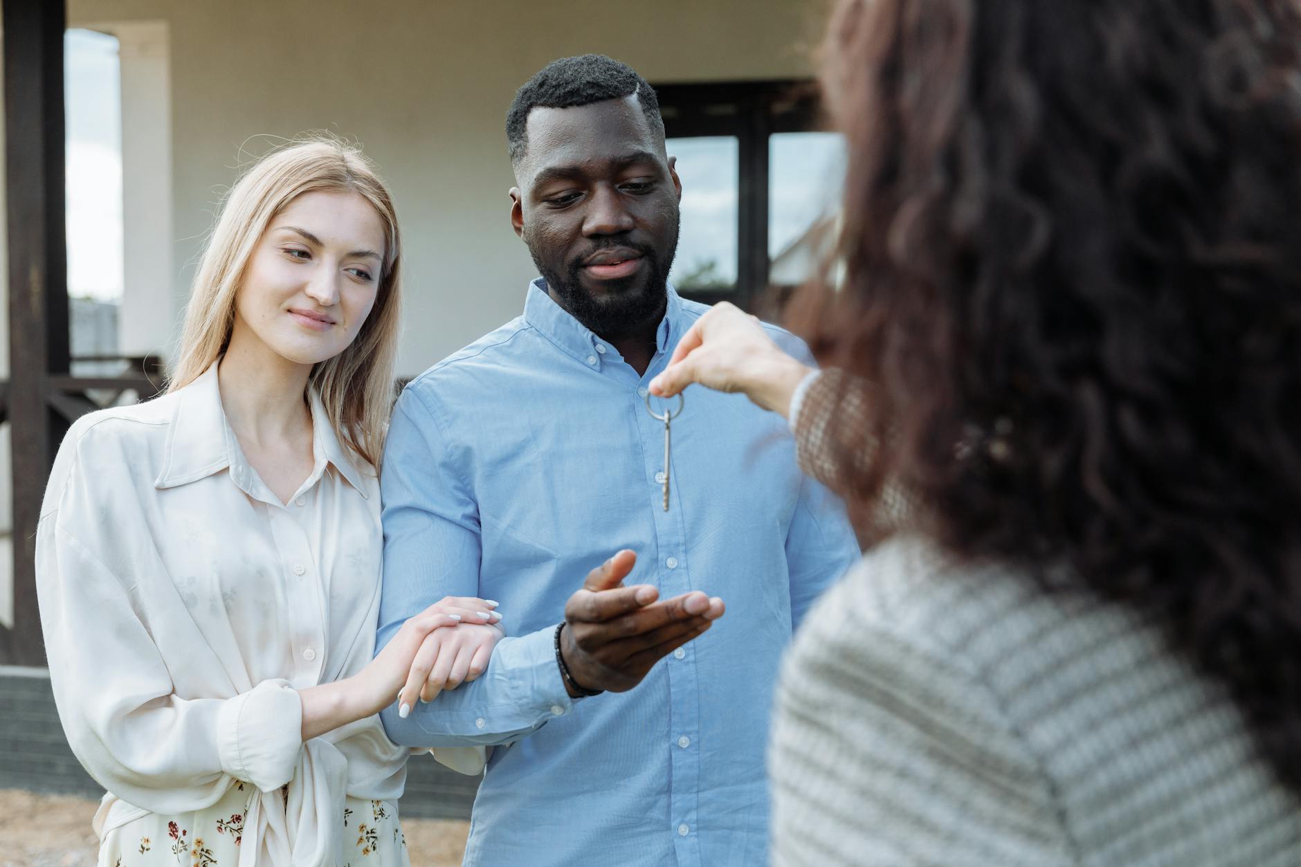 Real estate agent handing house keys to a happy couple outside their new home in New Hampshire