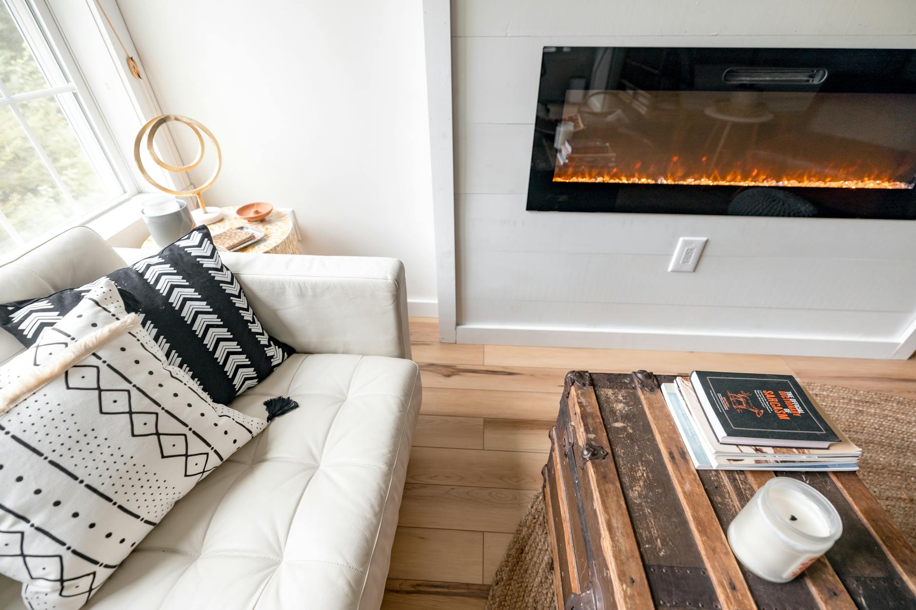 Cozy compact living room with a white sofa and wall-mounted electric fireplace — the low-maintenance space many downsizing NH homeowners are after