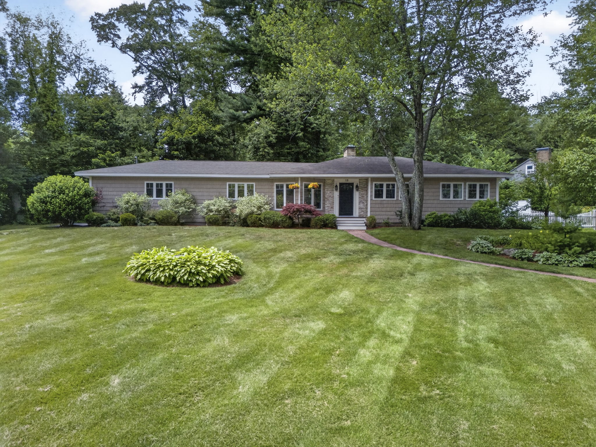 Single-story New England ranch home with tan shingle siding and a deep landscaped lawn, a strong candidate for a Merrimack NH ADU