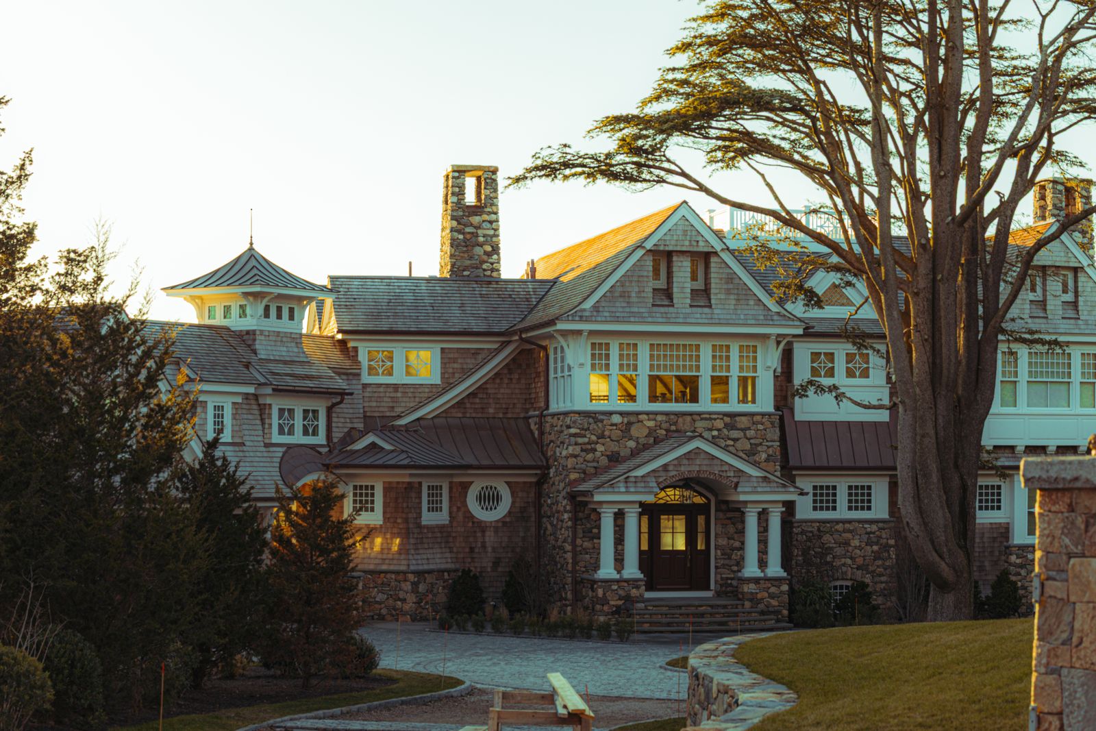 New England stone-and-shingle home on a green summer lot - safest towns in New Hampshire
