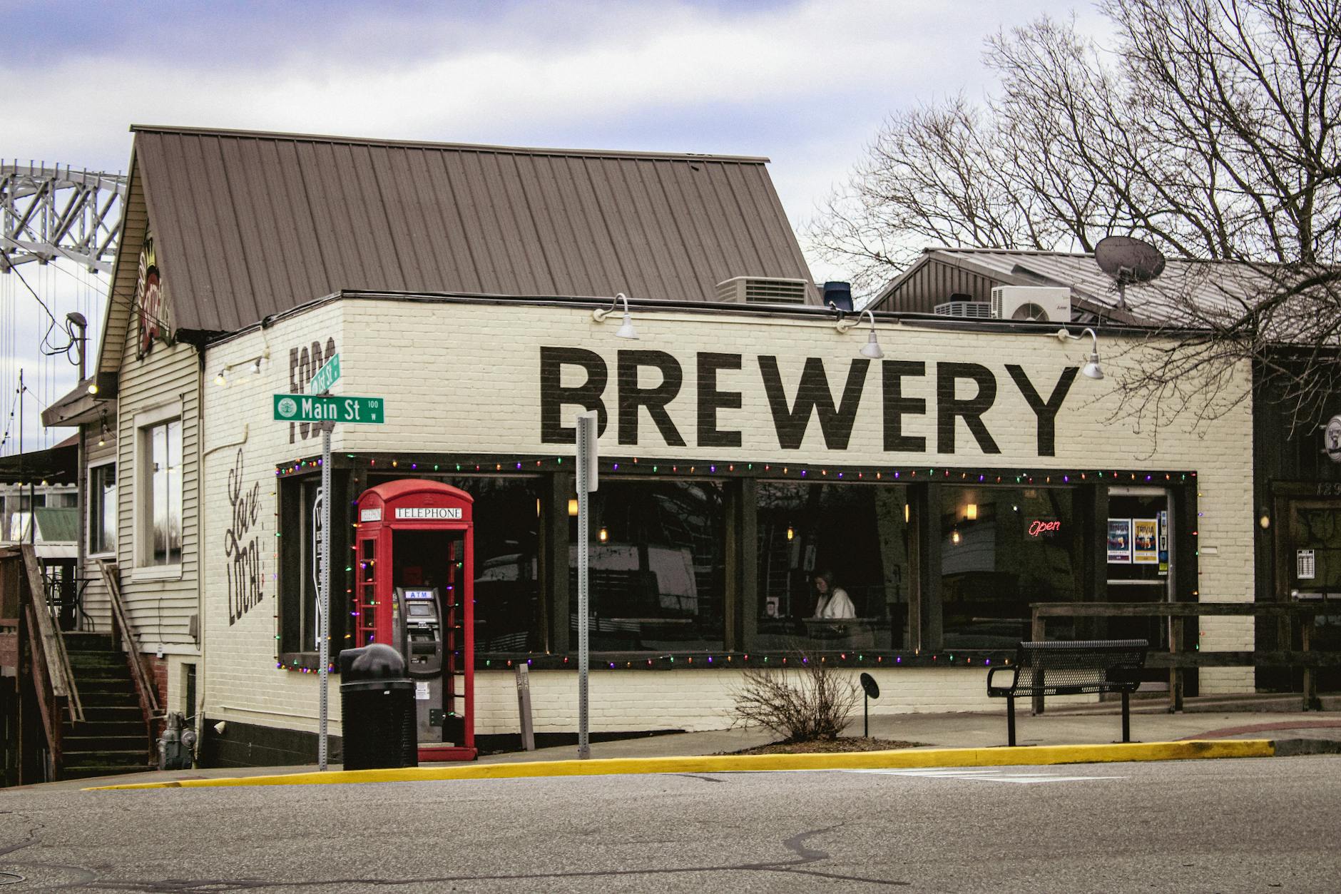 Historic brick brewery on a New England Main Street with red phone booth — the kind of historic streetscape found in the Manchester NH West Side neighborhood