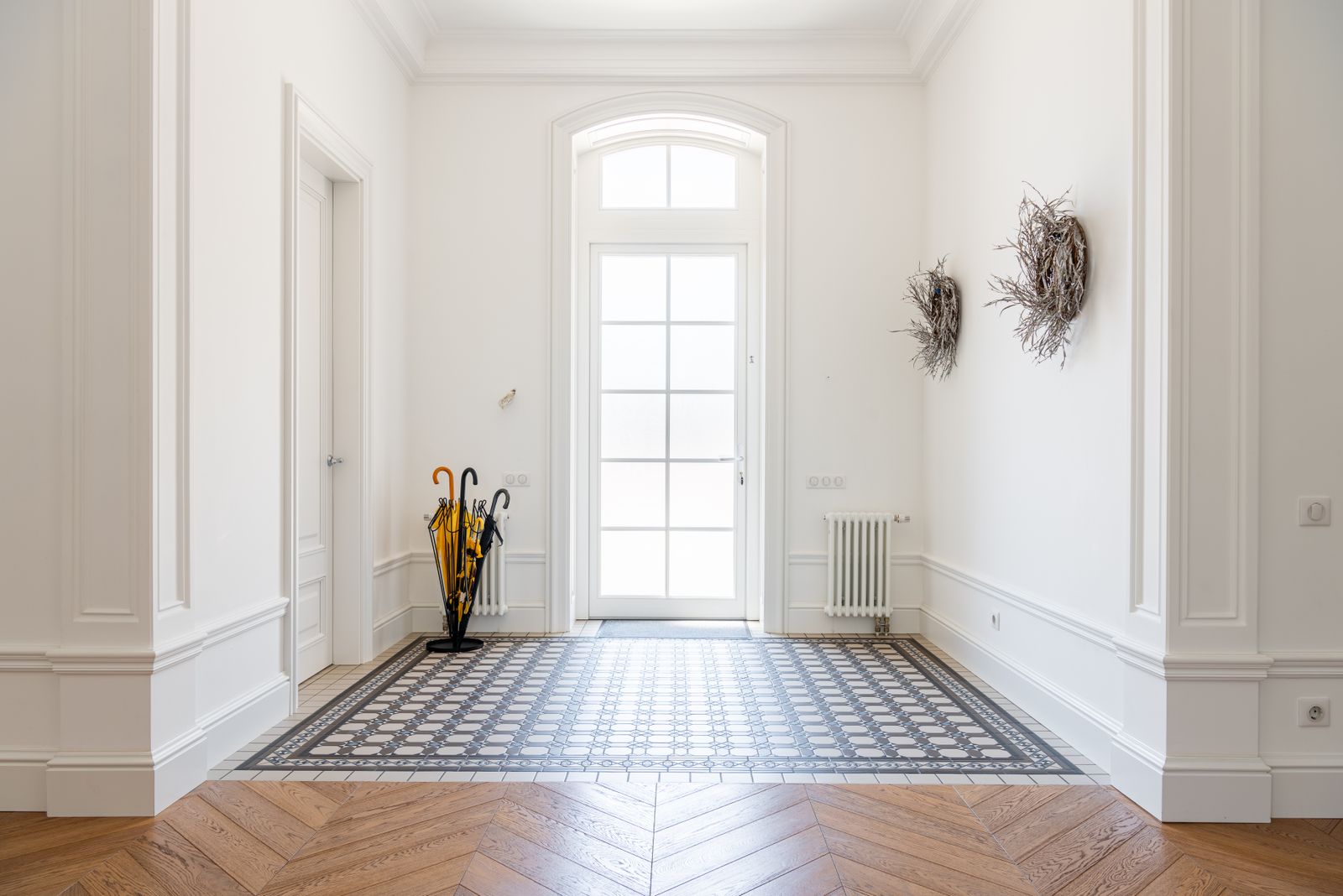 Bright entry hall with an arched glass door, patterned tile and herringbone wood floor - moving to New Hampshire from California