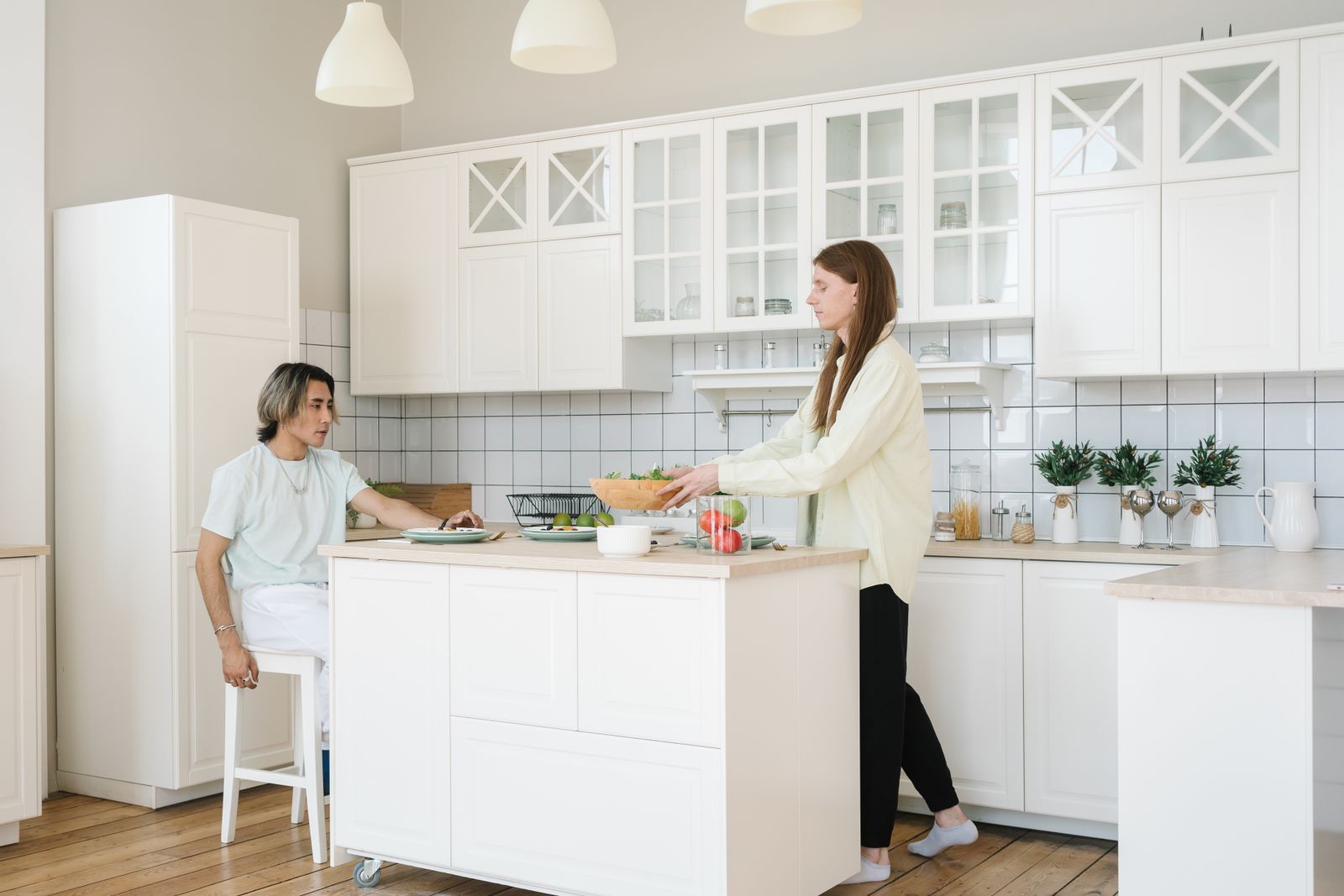 Two homeowners talking in a bright white kitchen while deciding how to choose a listing agent in New Hampshire