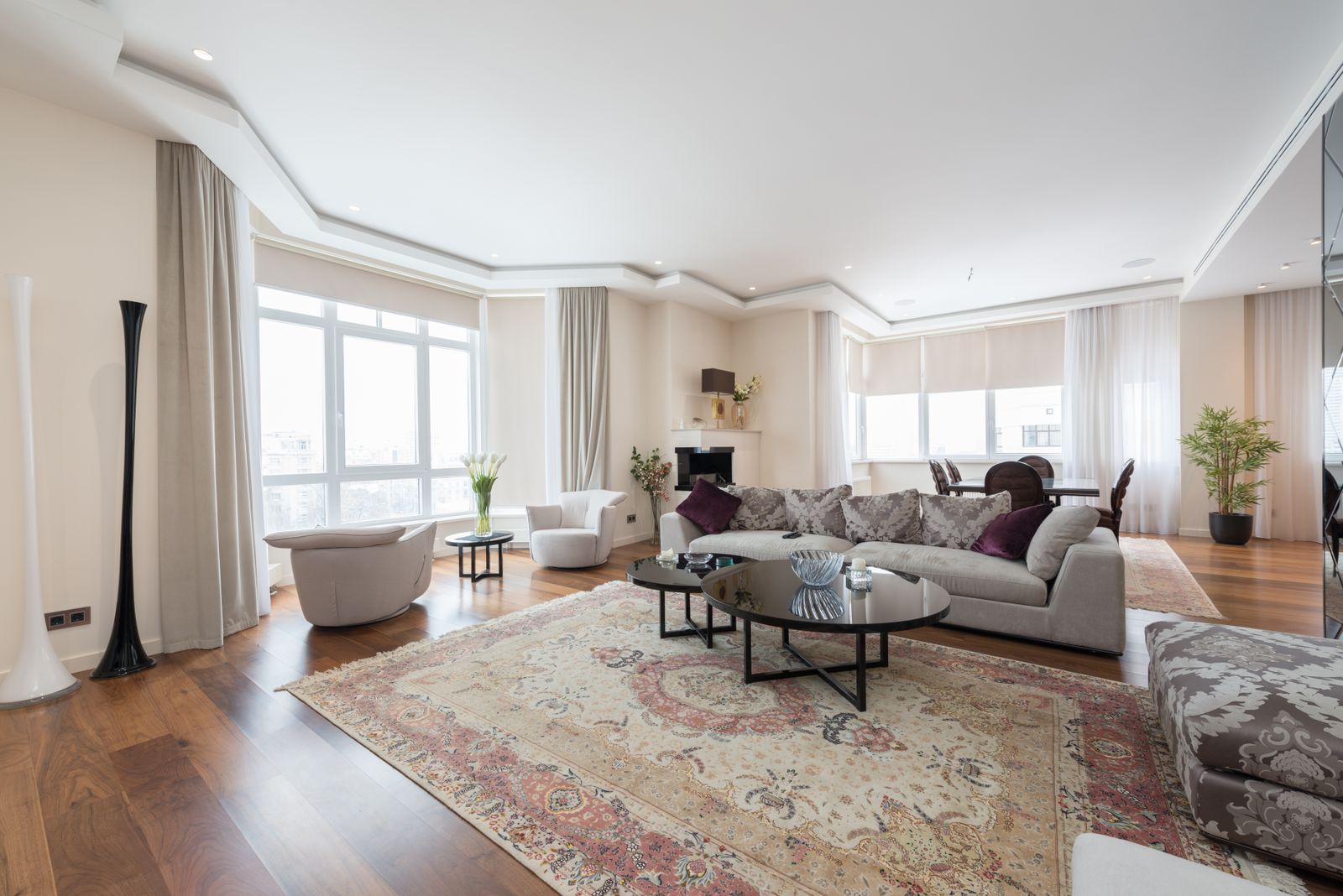 Staged living room with a neutral sectional sofa, patterned area rug and bright windows - how to stage a home in New Hampshire