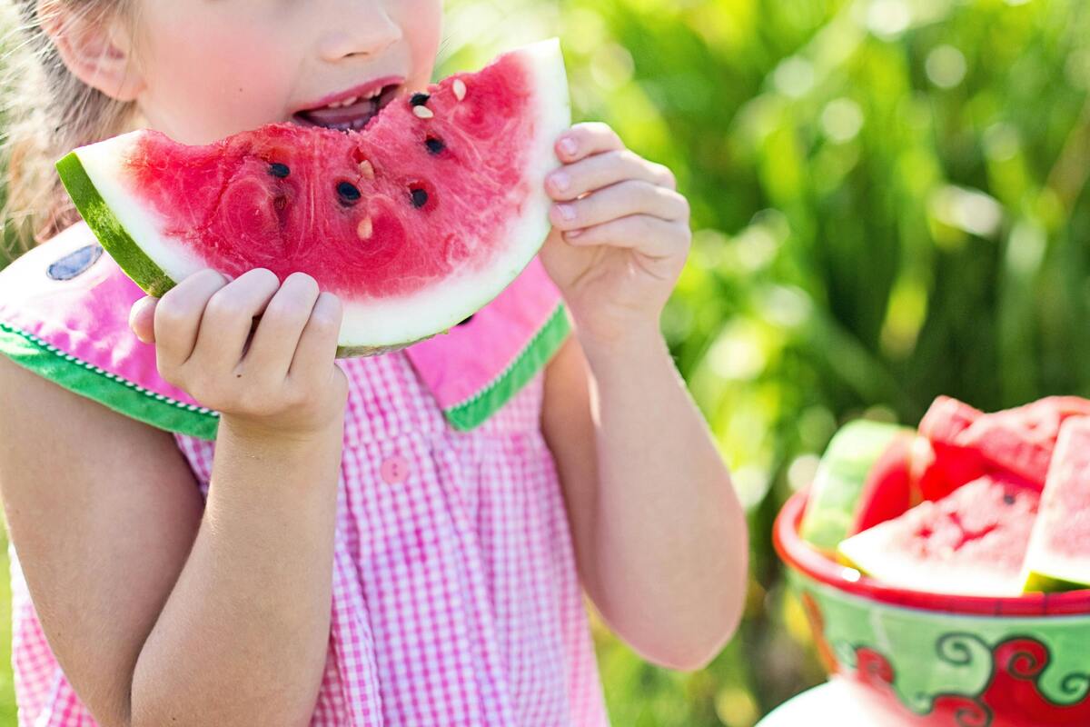 Kid eating watermelon in the summertime