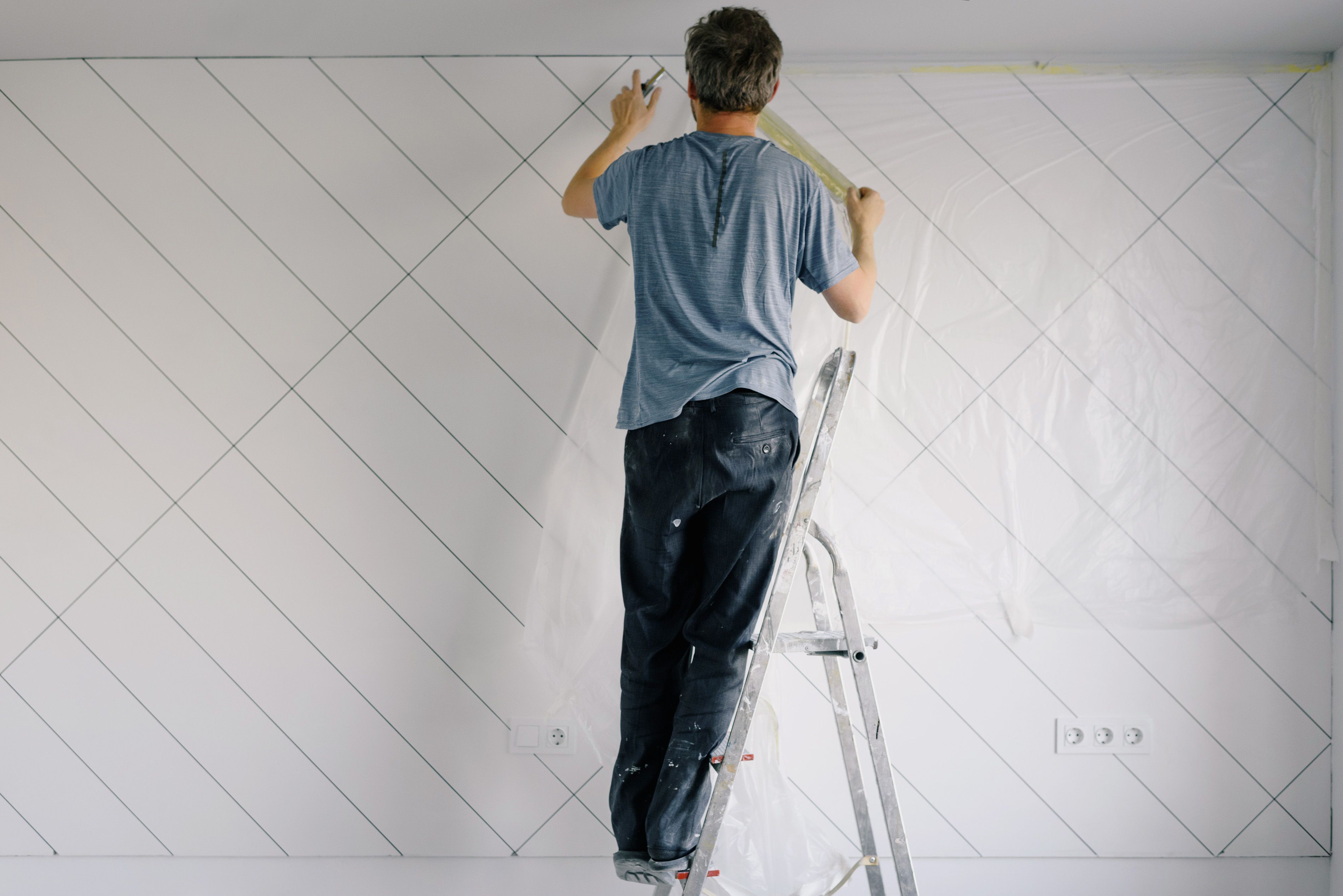 Man on ladder painting a wall
