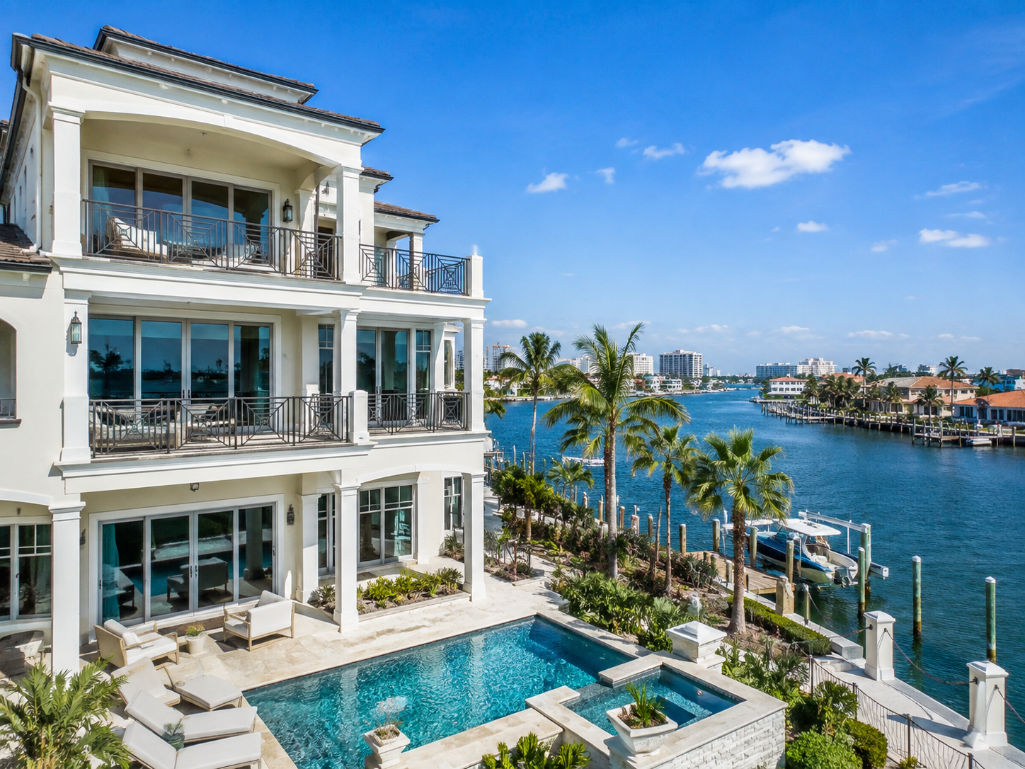 Luxury multi-story waterfront home with balconies, a pool, palm trees, private dock and views of the Intracoastal Waterway