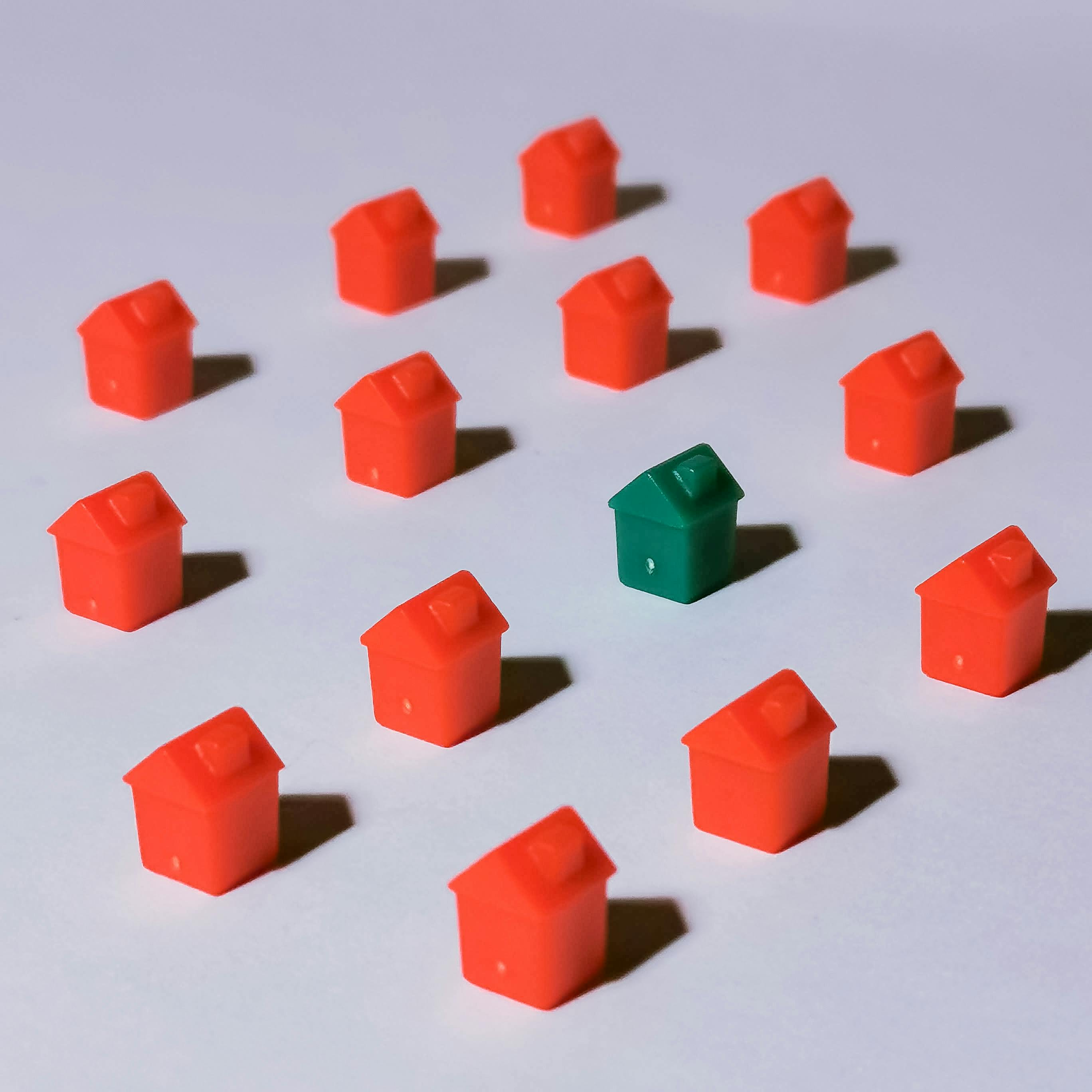 A green toy house surrounded by red toy houses