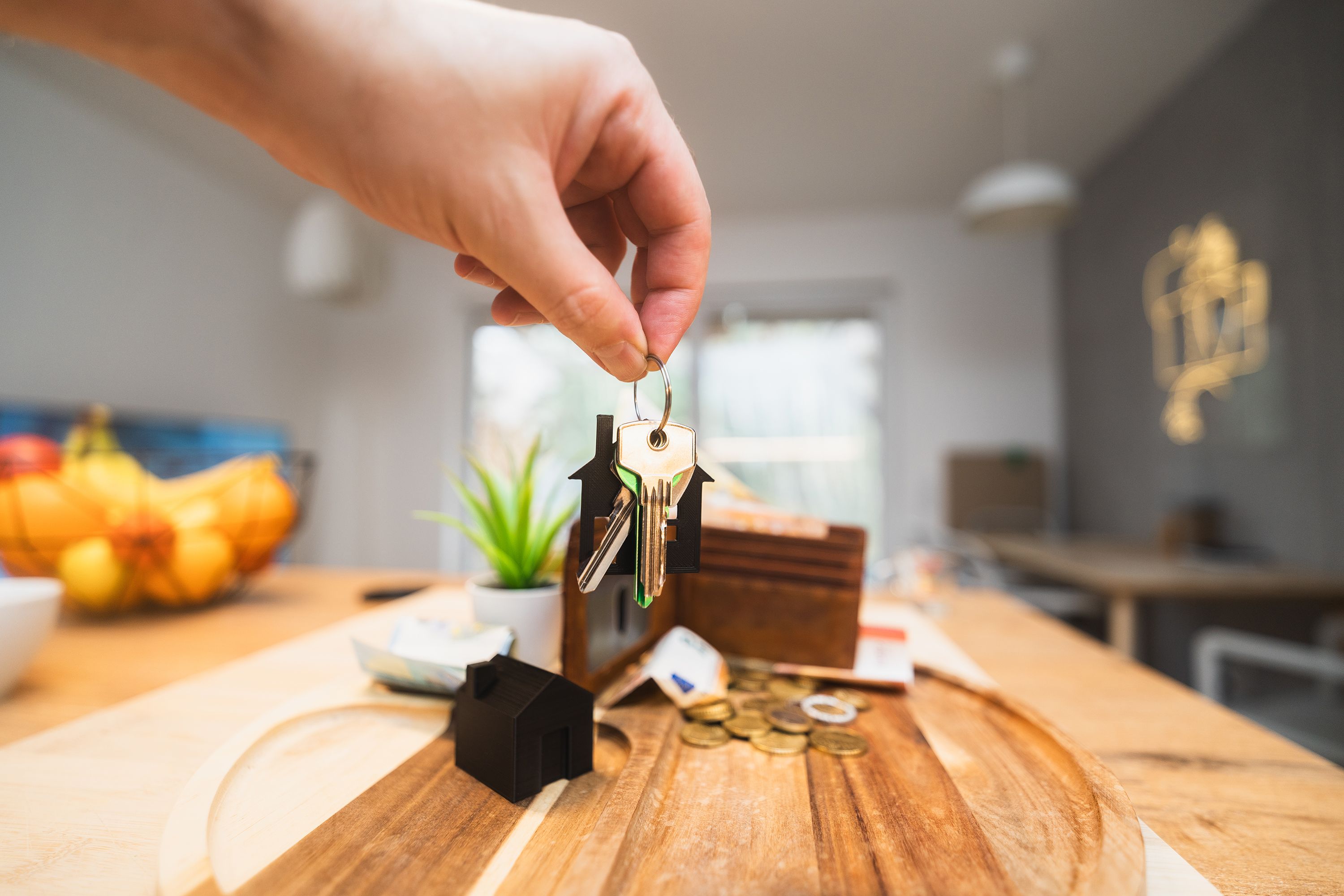 Hand holding a set of house keys over a kitchen table, for selling an inherited Maryland home