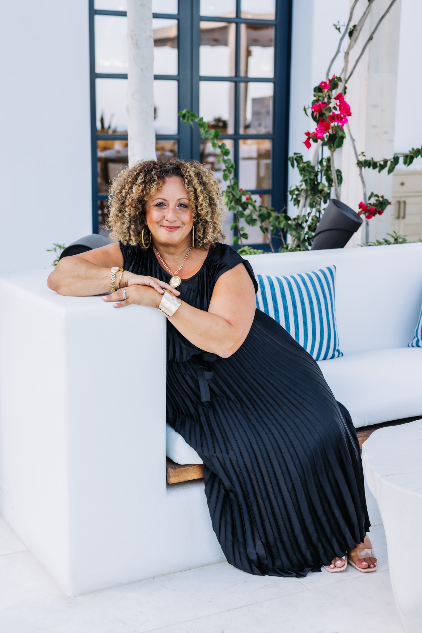 Melina Bradley sitting on a white couch in a pleated dress