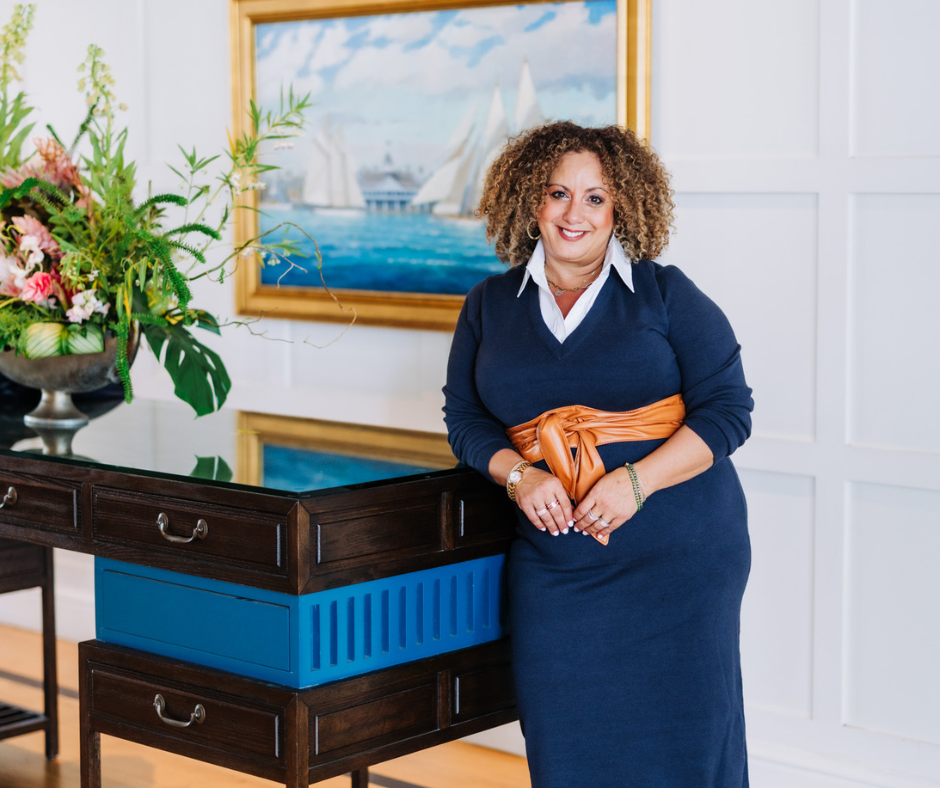 Melina standing in a luxury home wearing a blue dress