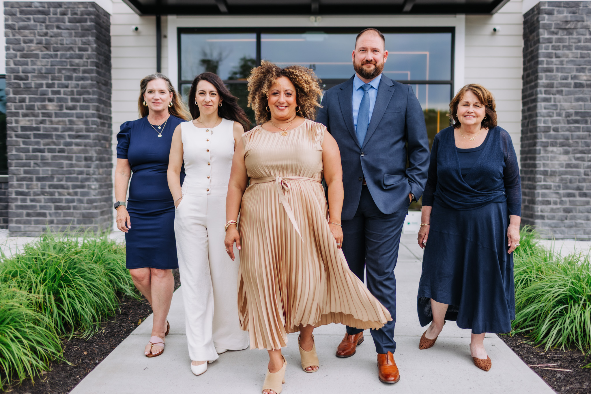 The Melina Bradley Real Estate Team left to right, Jackie in a blue dress, Melissa in a white dress , Melina in a gold dress , Jeremy in a blue suit and Lorraine in a blue dress