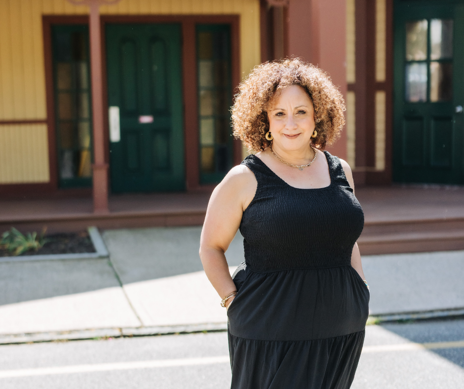 Melina standing in front of a building in a black dress
