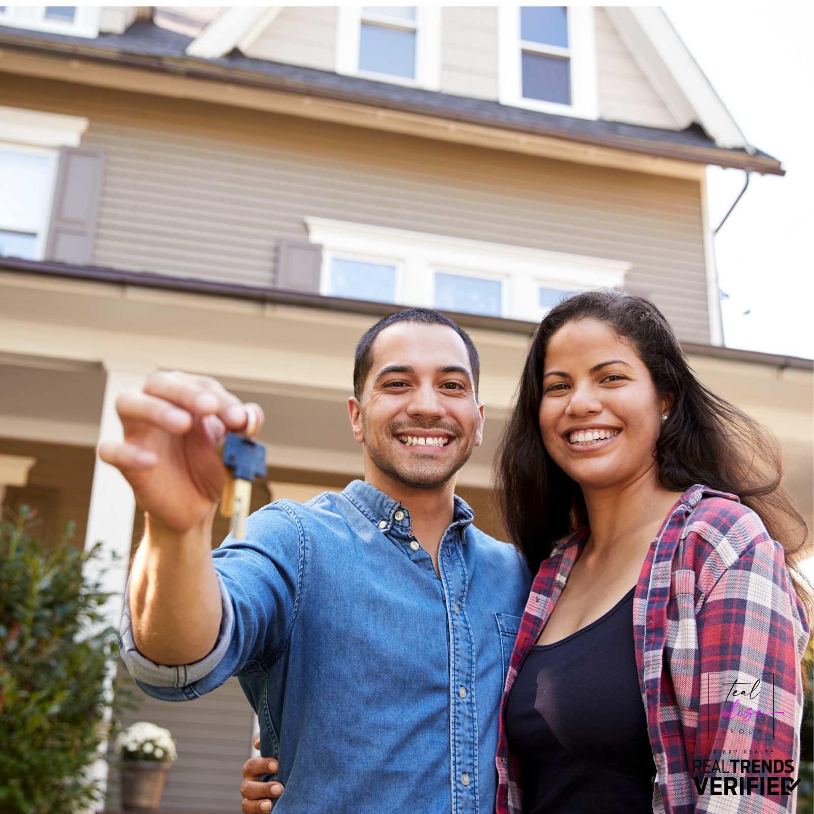 Smiling couple holding house keys in front of their new home, representing how home equity can help buyers make their next move.