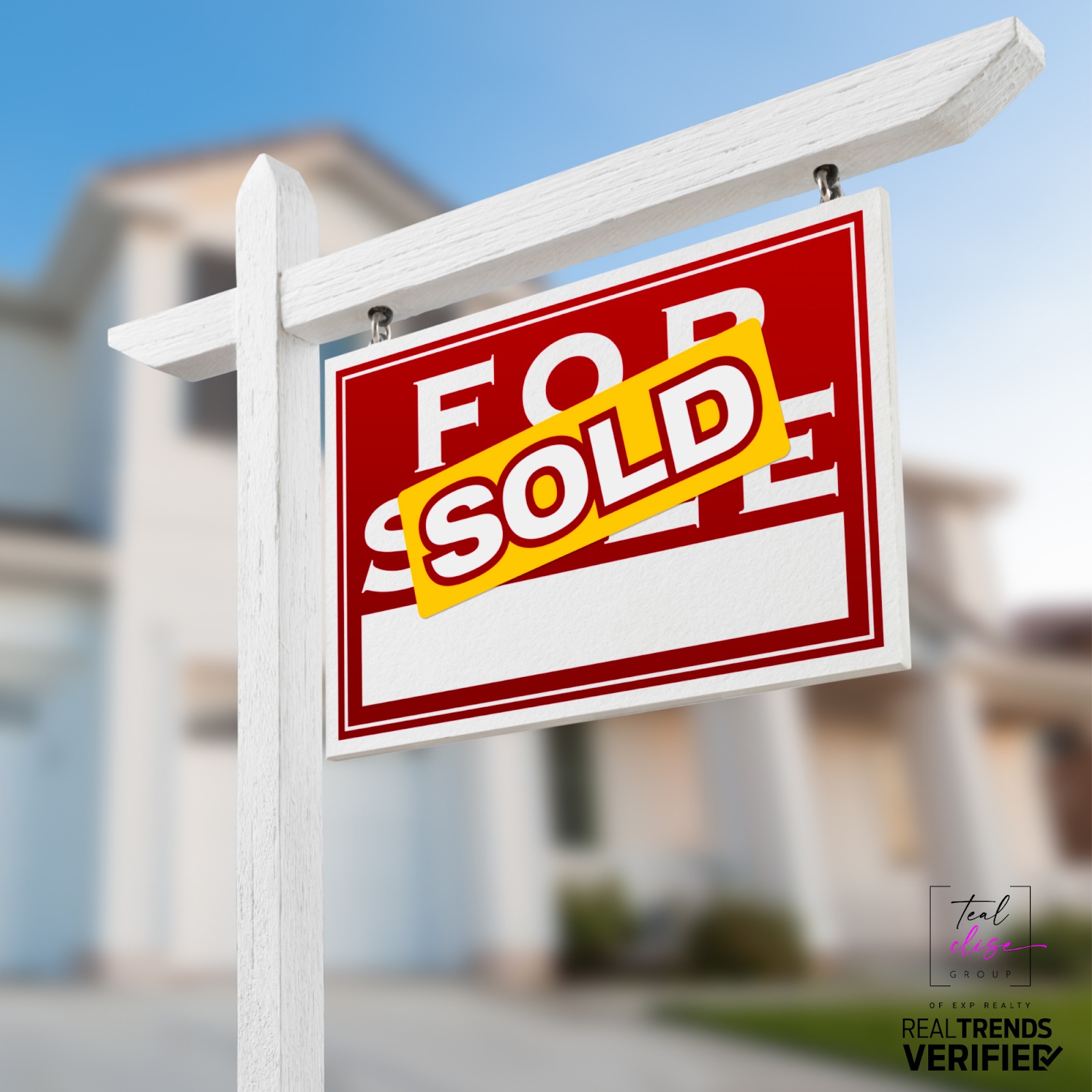 Close-up of a red and white ‘For Sale’ sign with a yellow ‘SOLD’ sticker, standing in front of a modern suburban home. The blurred house in the background represents a successful home sale by the Teal Clise Group, a RealTrends Verified Maryland real estate team.