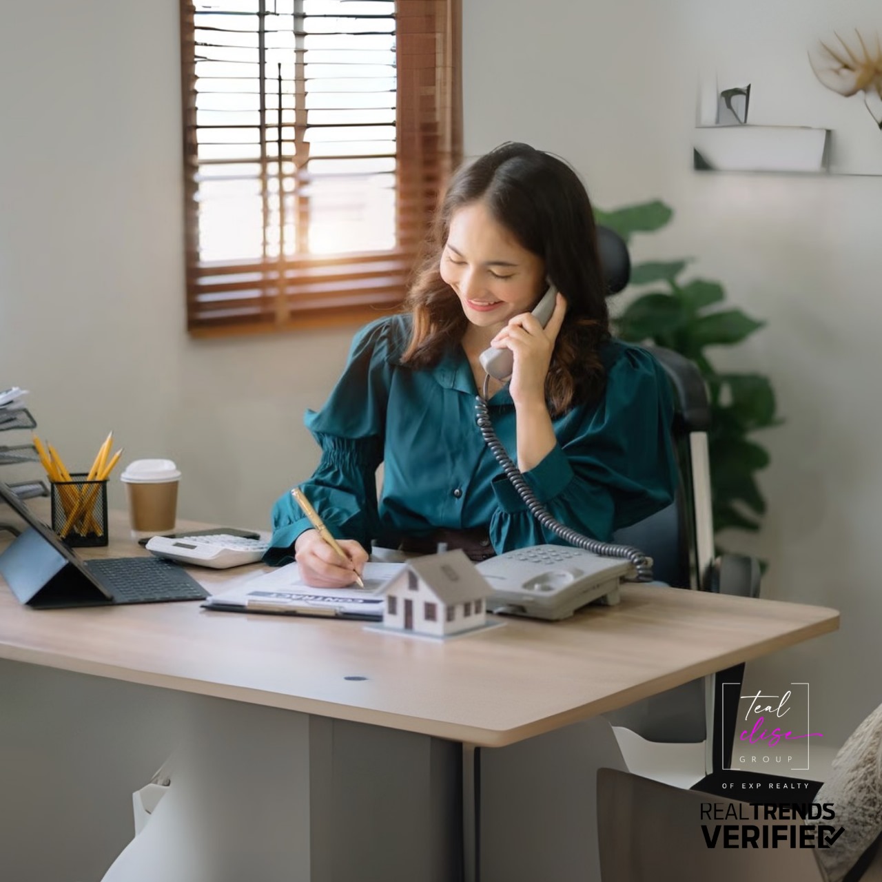 Realtor on the phone at her desk with a laptop, calendar and coffee showcasing the daily hustle behind the scenes of a top Maryland real estate team.
