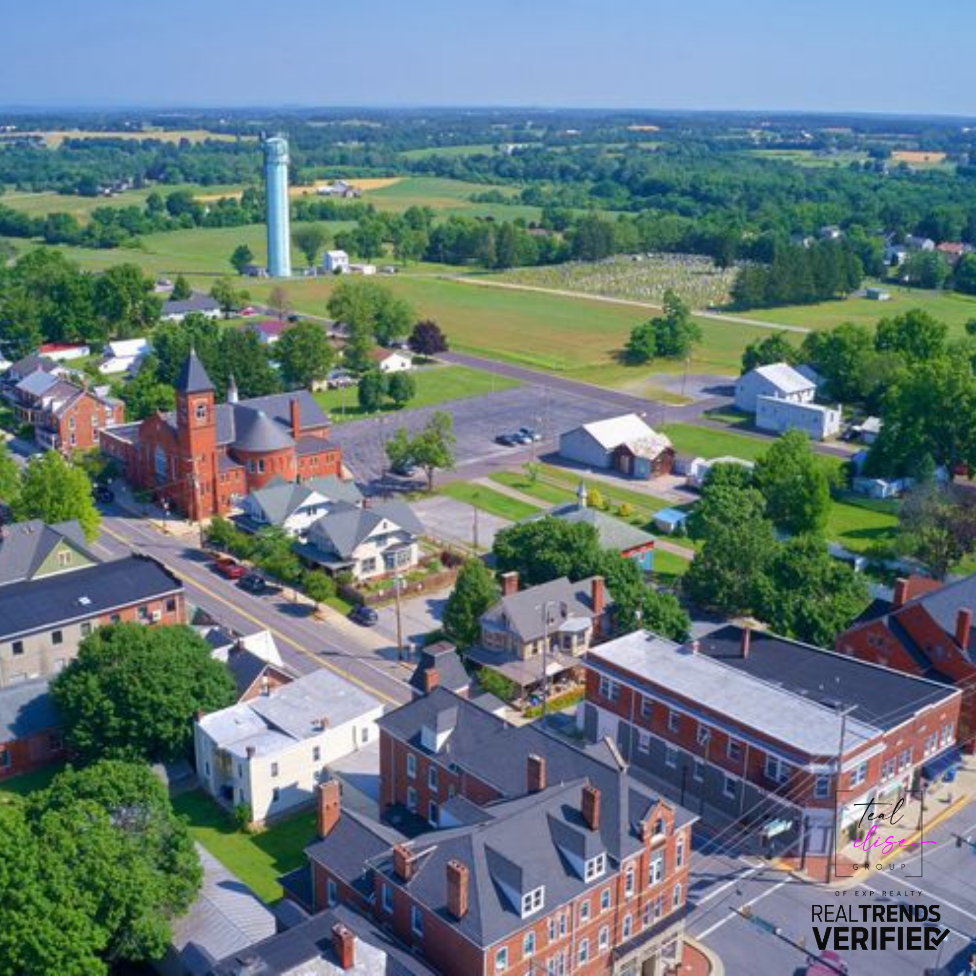Aerial view of a small town in Carroll County, Maryland, showing historic brick buildings, green farmland, and open skies.