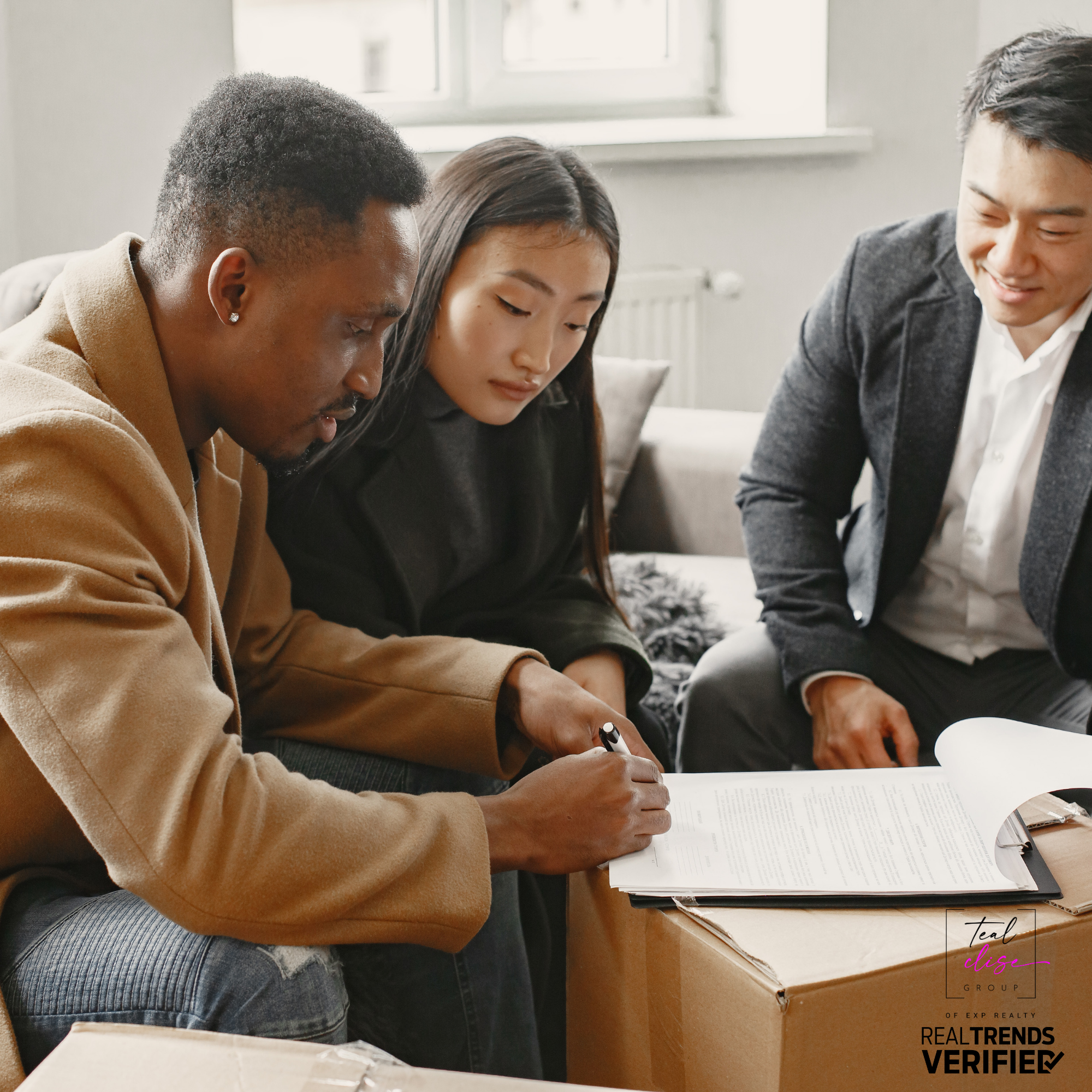 Maryland home sellers signing real estate documents with an agent, surrounded by moving boxes in a modern living room. The image represents the home selling process and highlights the importance of working with a local real estate professional to avoid costly mistakes.