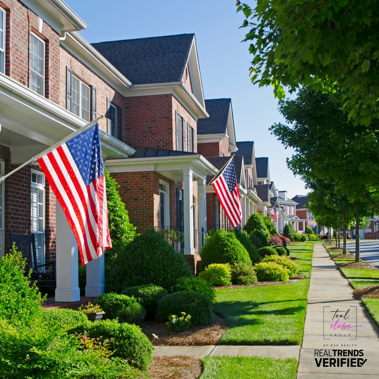 Row of traditional brick homes with manicured lawns and American flags displayed on each porch, lining a quiet suburban street representing patriotic neighborhoods near Maryland military bases like Fort Meade and Aberdeen Proving Ground.