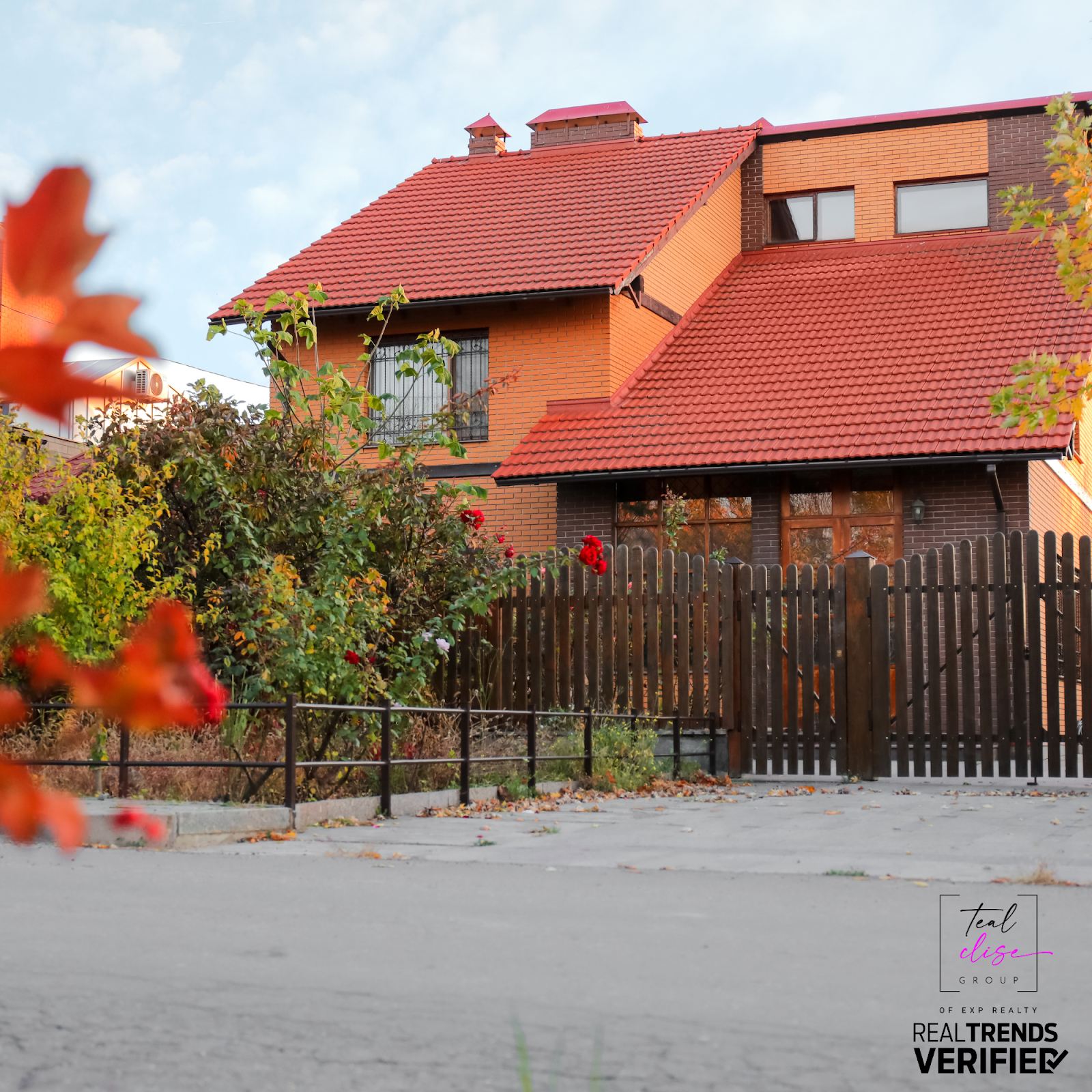Brick house with red roof and fall foliage in front yard, representing cozy Maryland homes during the autumn real estate season.