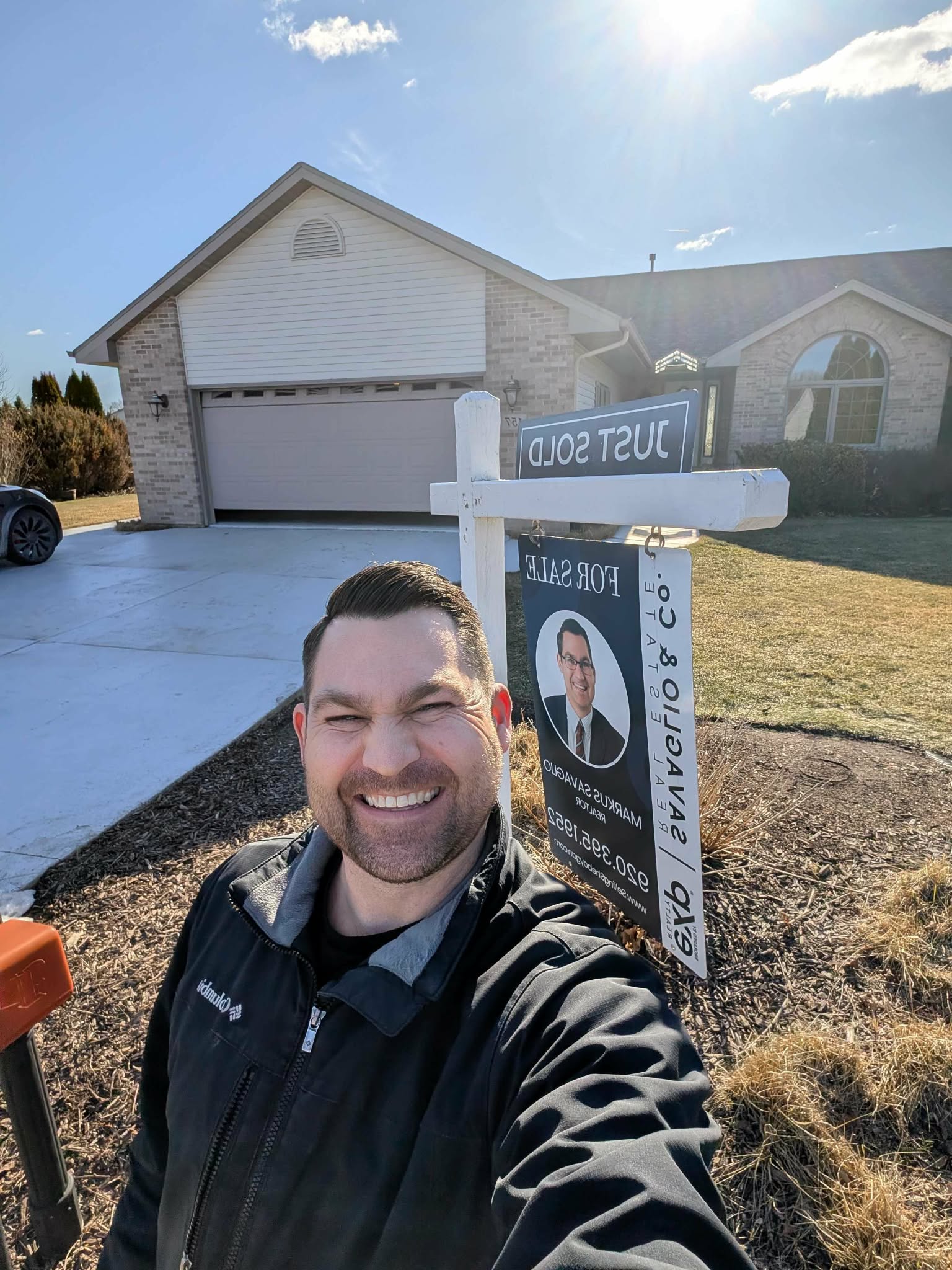 Markus Savaglio in front of a home with a Just Sold sign