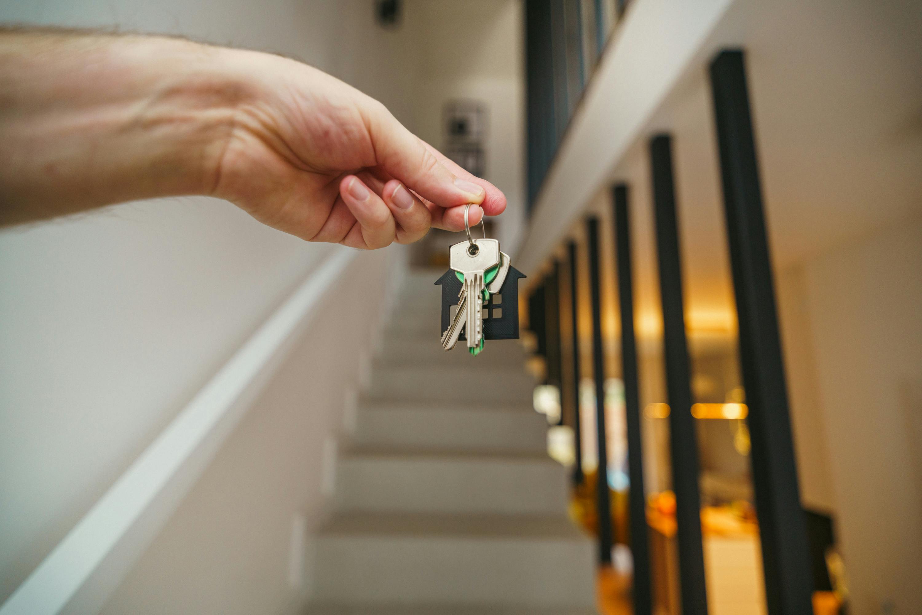 Close-up of a hand holding house keys inside a new home, symbolizing a successful home purchase.