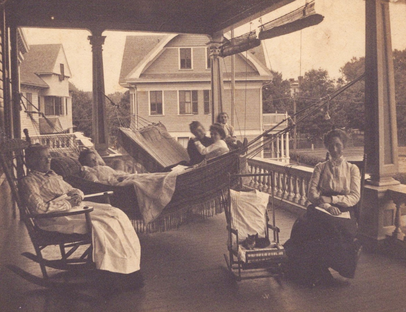 Vintage Photo of a 1800s family sitting on a porch with rocking chairs and a hammock