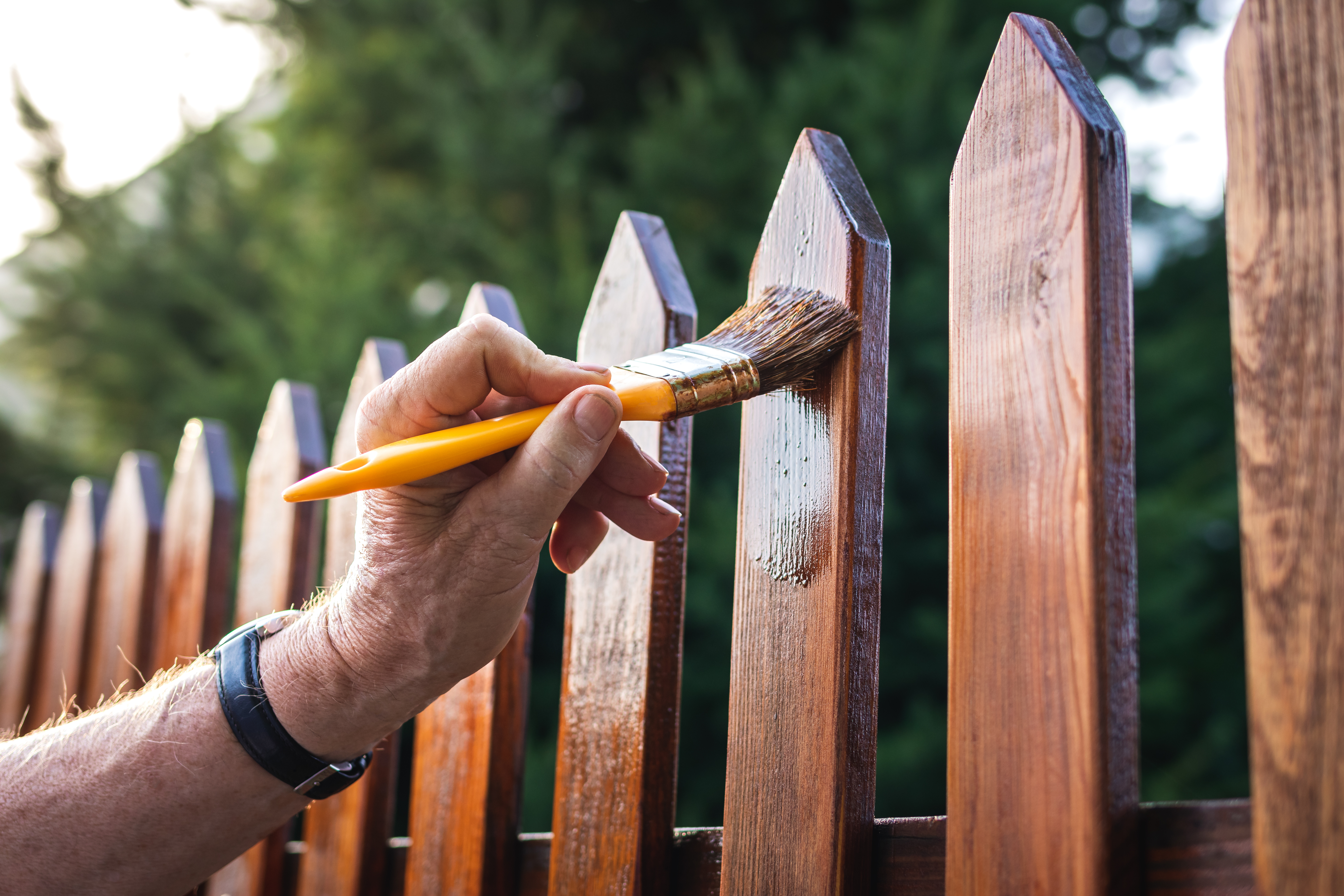 Re-staining a fence as part of summer home maintenance