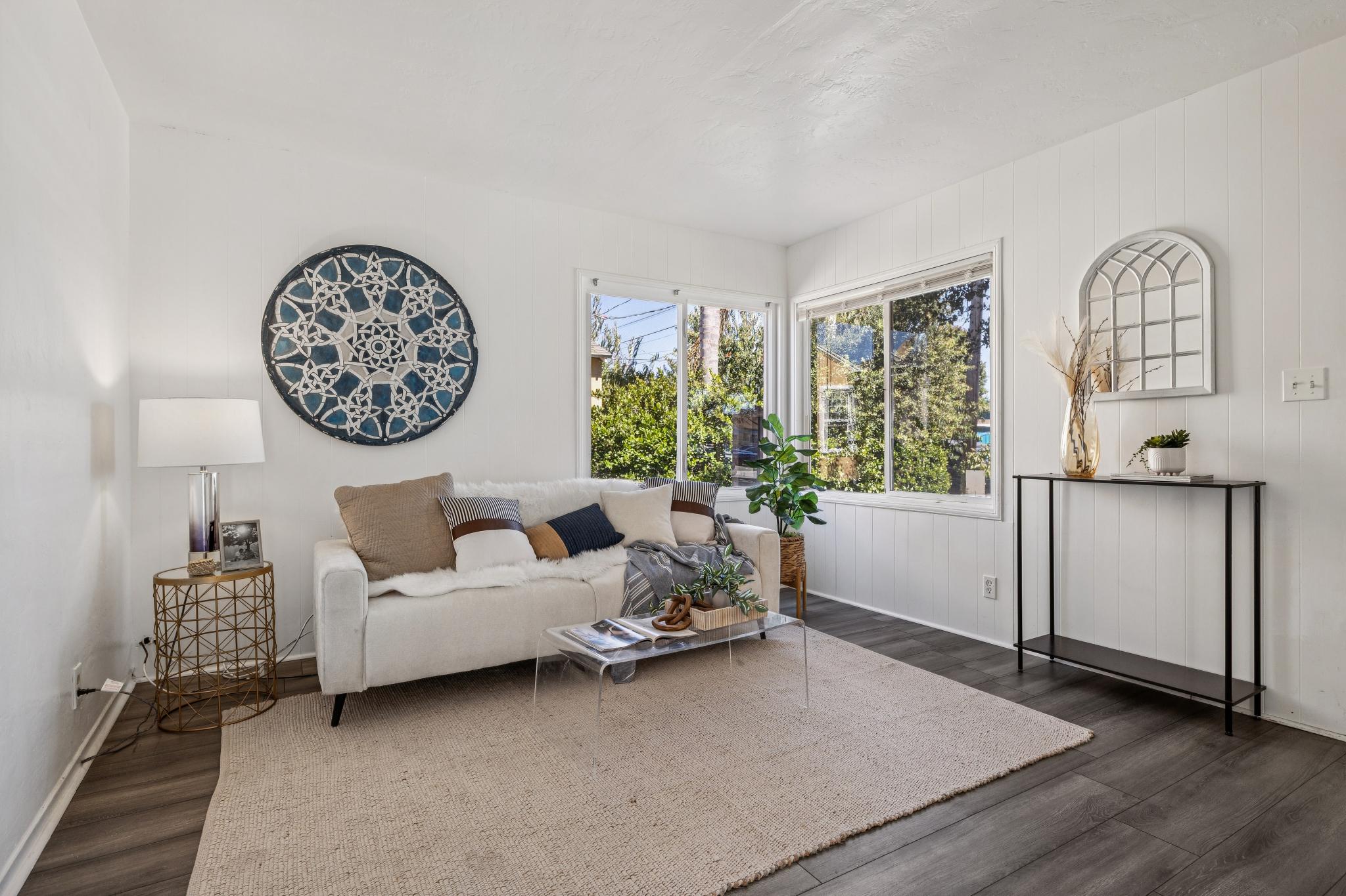 Bright living room with large windows, white paneled walls, dark flooring, and staged seating at 3417 Maricopa Ave in Richmond, CA.