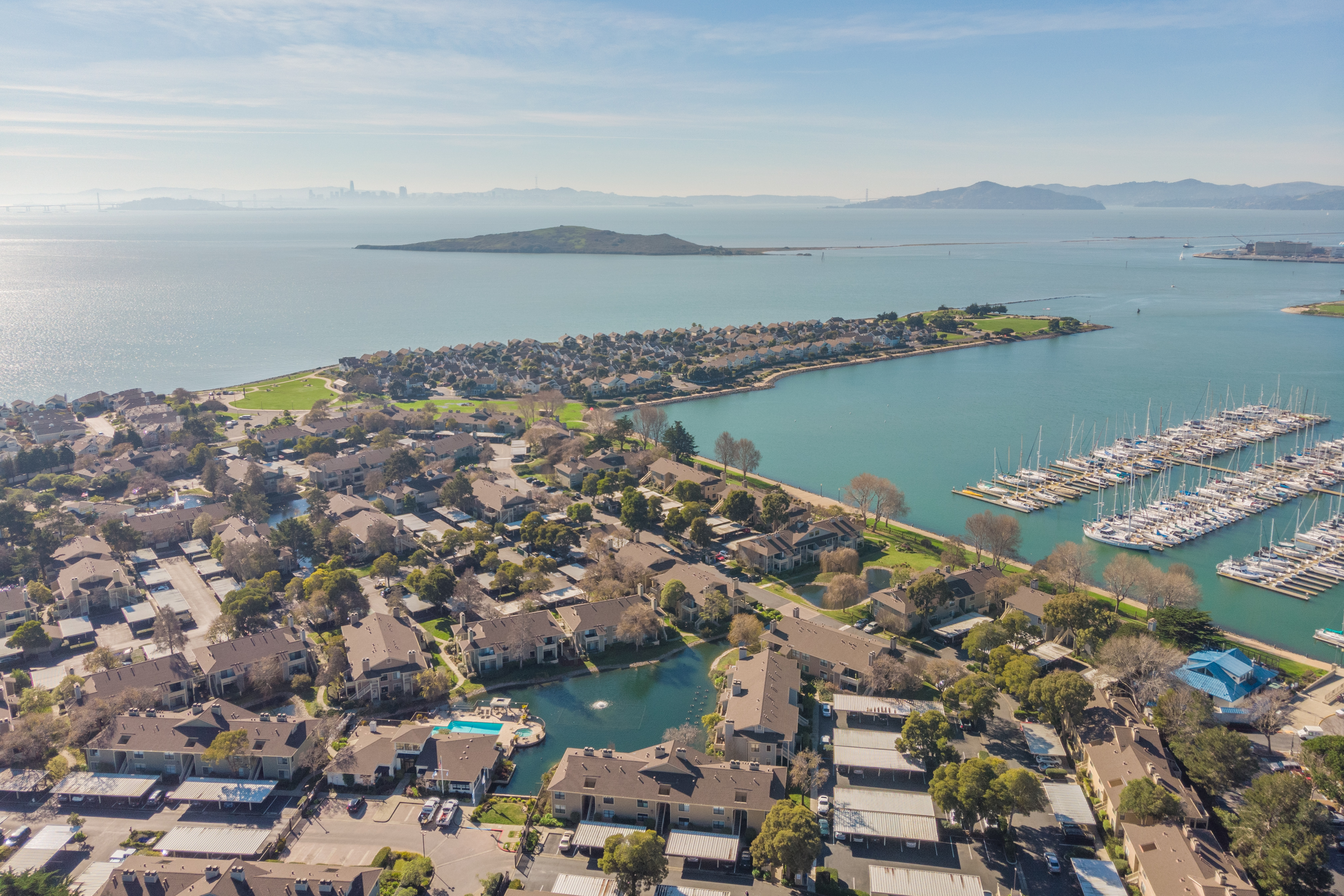 Aerial view of Marina Bay near 24 Bayside Ct in Richmond, California, with waterfront homes, marina docks, San Francisco Bay, and distant skyline.