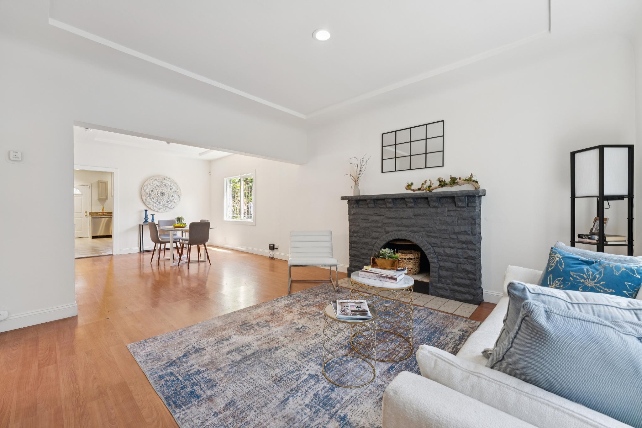 Bright living room with dark stone fireplace, hardwood floors, and open dining area at 220 Marina Way in Richmond, CA.