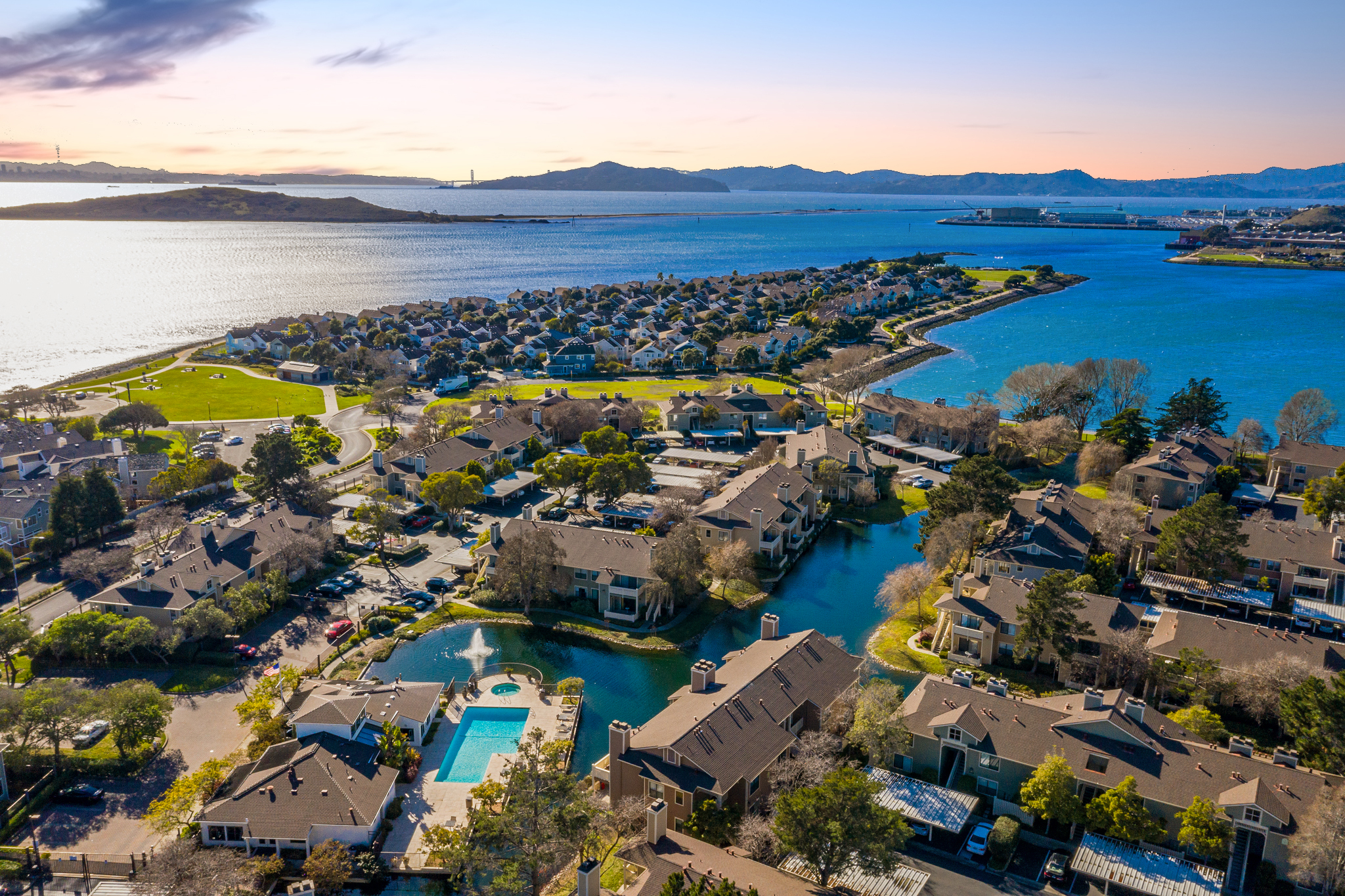 Aerial view of Marina Bay in Richmond, California, showing waterfront homes, lagoons, a community pool, and the San Francisco Bay.