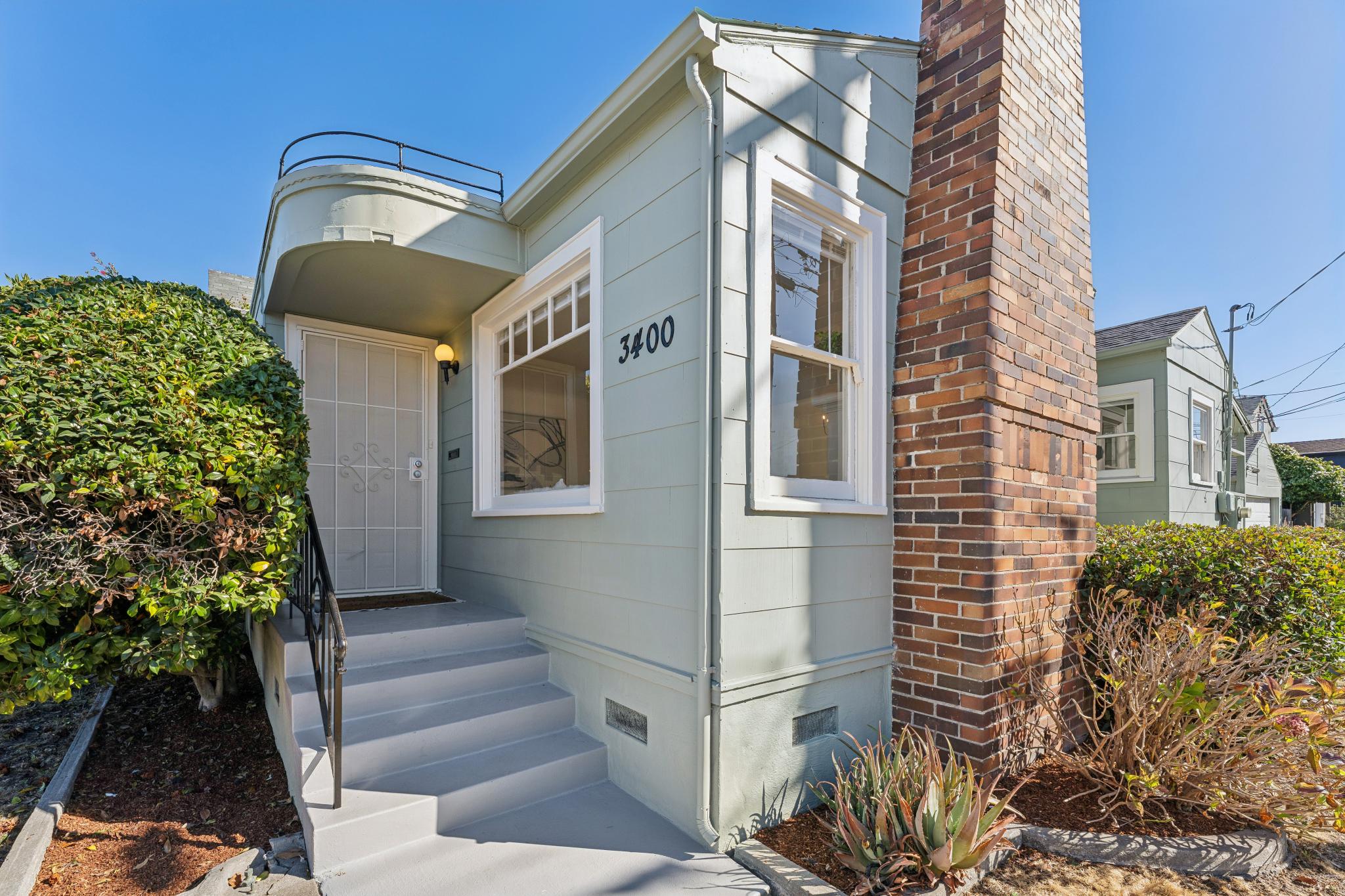 Front exterior with brick chimney, entry canopy and corner yard at 3400 McBryde Ave in North and East, Richmond, CA