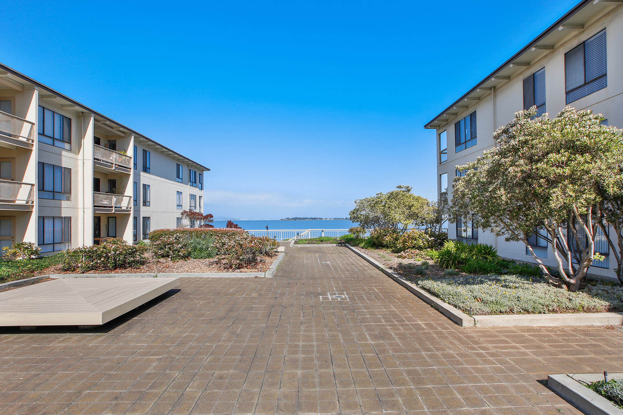 Landscaped courtyard between Watergate condominium buildings with a clear view of the San Francisco Bay.