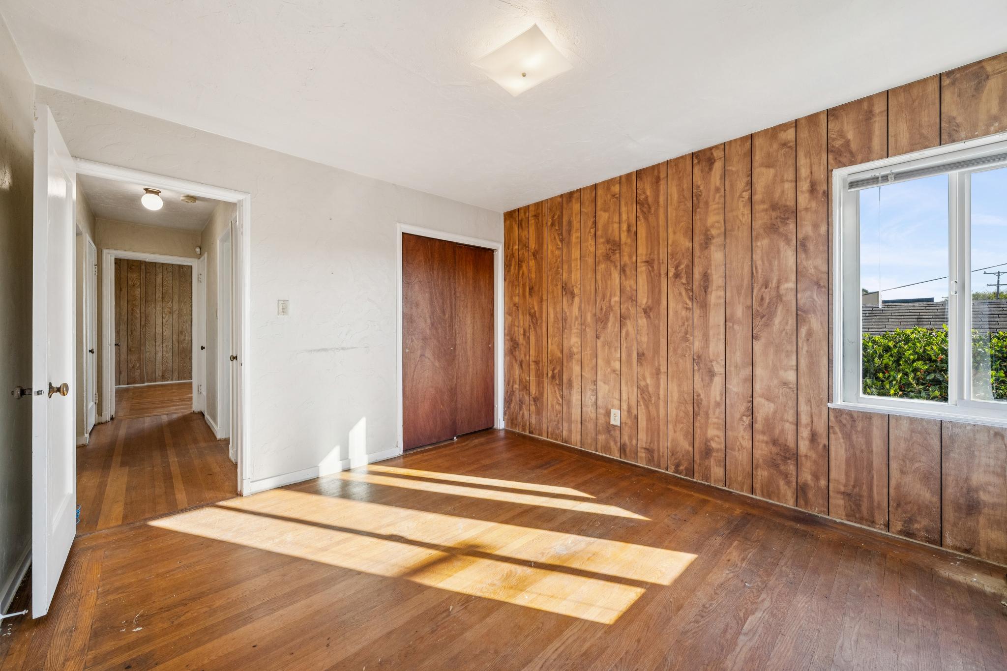 Upstairs bedroom with wood-paneled walls and hardwood floors at 974 33rd St, North and East, Richmond