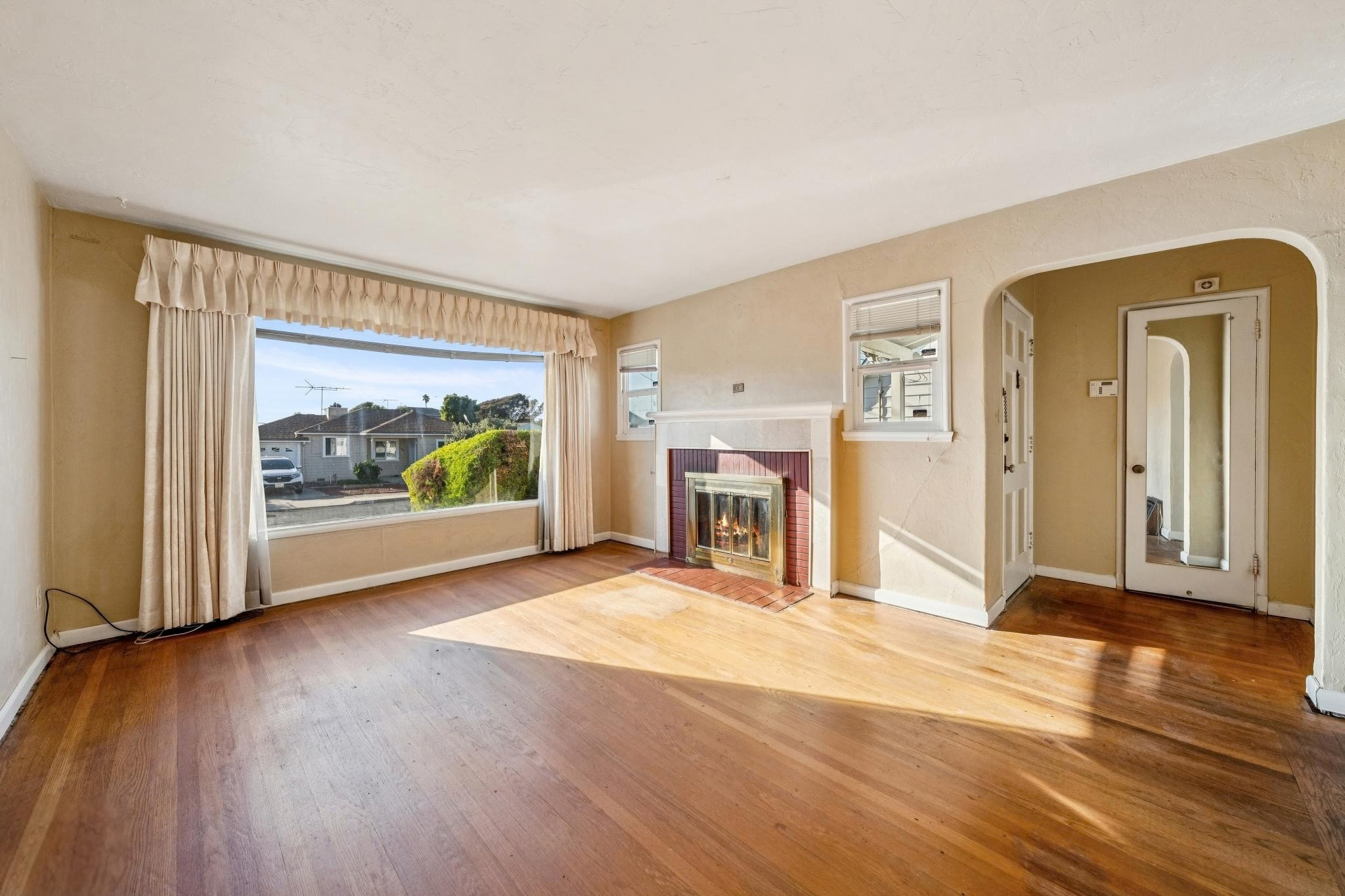 Living room with hardwood floors, broad front window and lit fireplace at 974 33rd St, North and East, Richmond