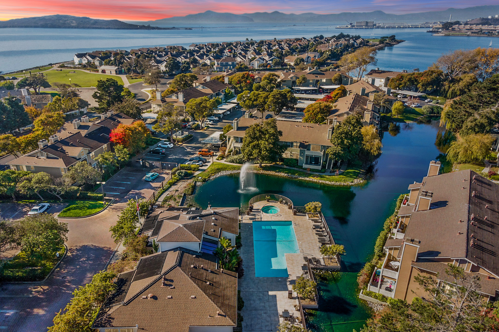 Aerial view of Marina Bay in Richmond, showing waterfront condos, a lagoon and fountain, shared pool and hot tub, and San Francisco Bay.