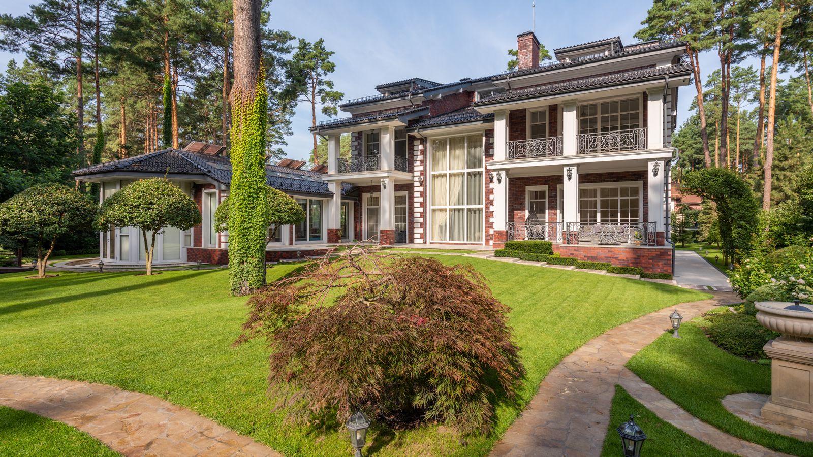 Large luxury home surrounded by tall trees and manicured landscaping