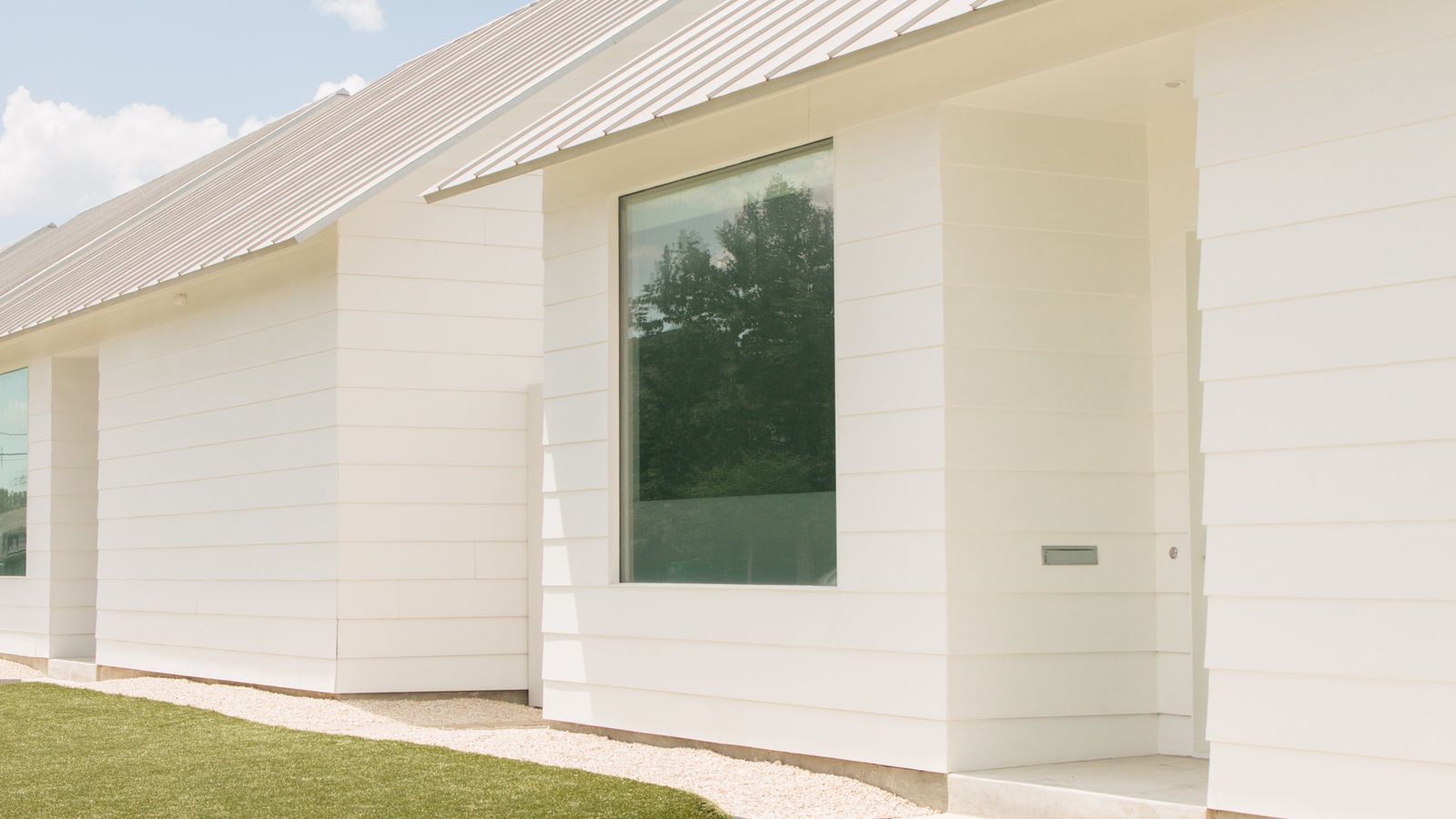 White modern Texas home exterior with a metal roof on a sunny day