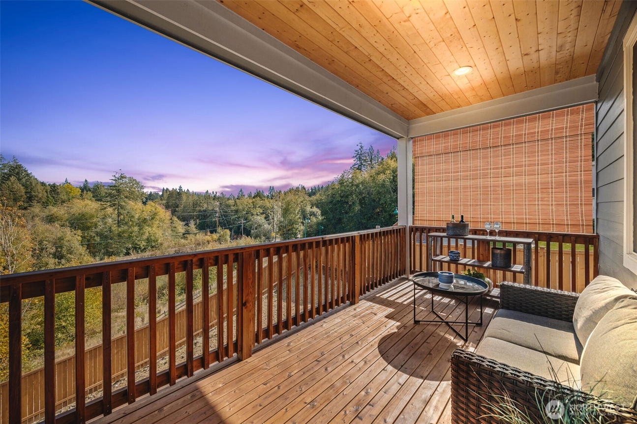 Covered outdoor deck overlooking wooded scenery in a South Sound home, professionally photographed to showcase outdoor living spaces by Heather Redal and Redal Homes.