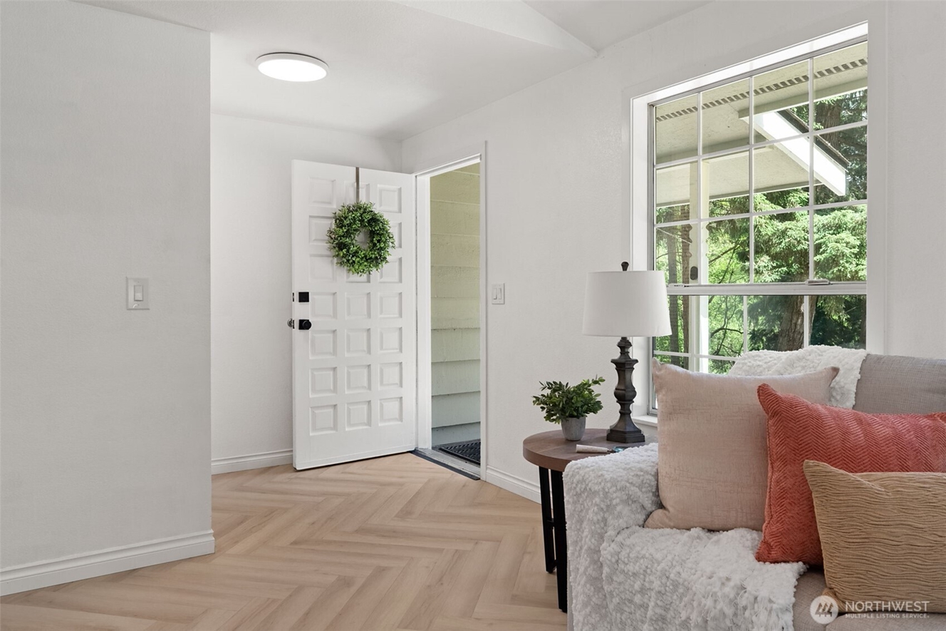 Bright, welcoming entryway in a Washington home with modern flooring, natural light, and views of mature evergreen trees, representing homeownership opportunities for military families using VA loans.