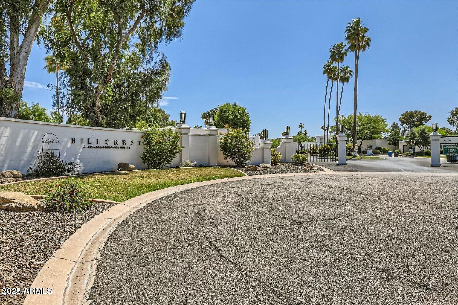 Street view of Hillcrest Moon Valley showing mature trees, well-maintained Dell Trailor ranch homes, and mountain backdrop
