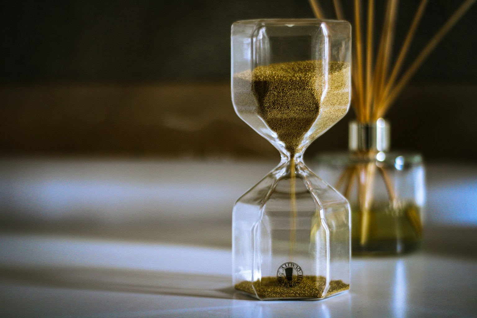 Golden sand flowing through an hourglass in warm sunlight, symbolizing seasonal timing and opportunity for home sales