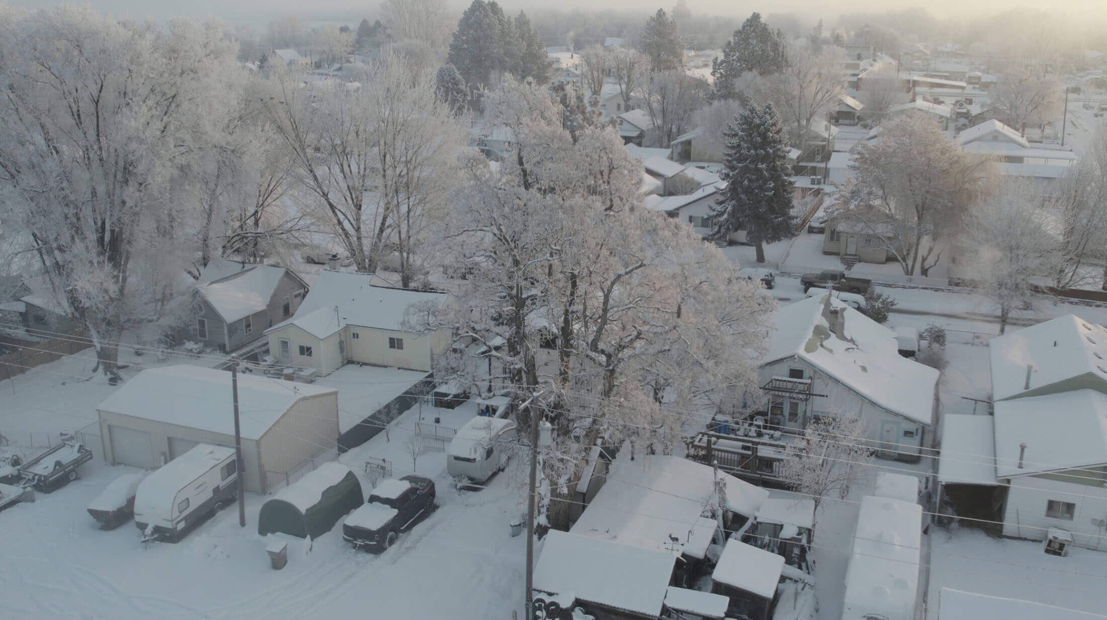 A cozy suburban home glowing from the windows at dusk with a light layer of snow on the roof.