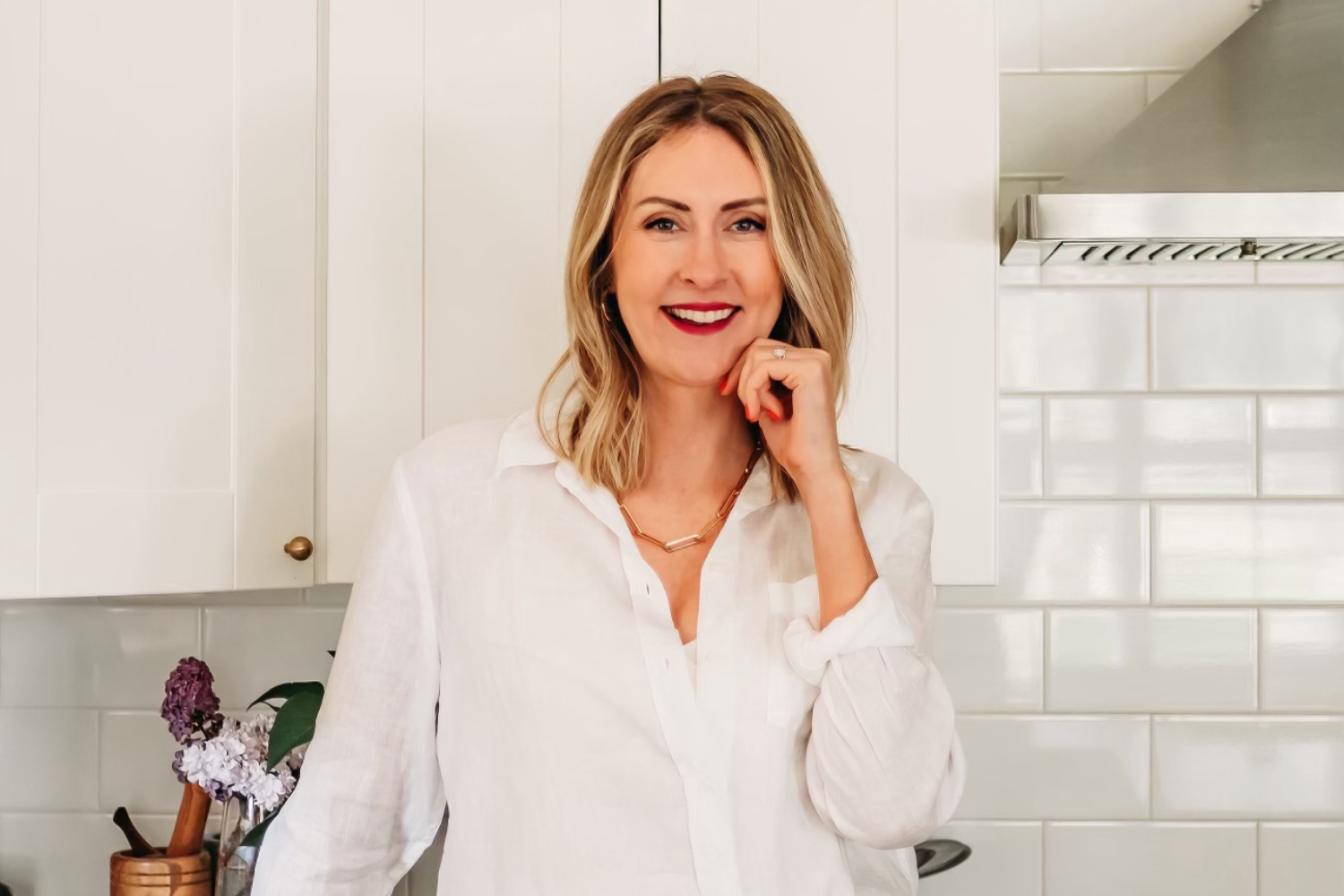 Lindsay Loreen, real estate agent posing in a white-tiled kitchen.