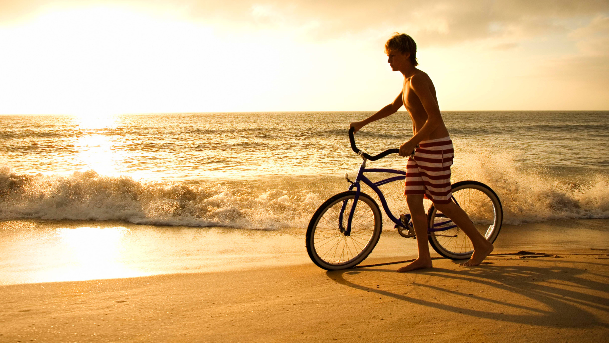 Person standing on Jacksonville Beach with a beach cruiser at sunrise.